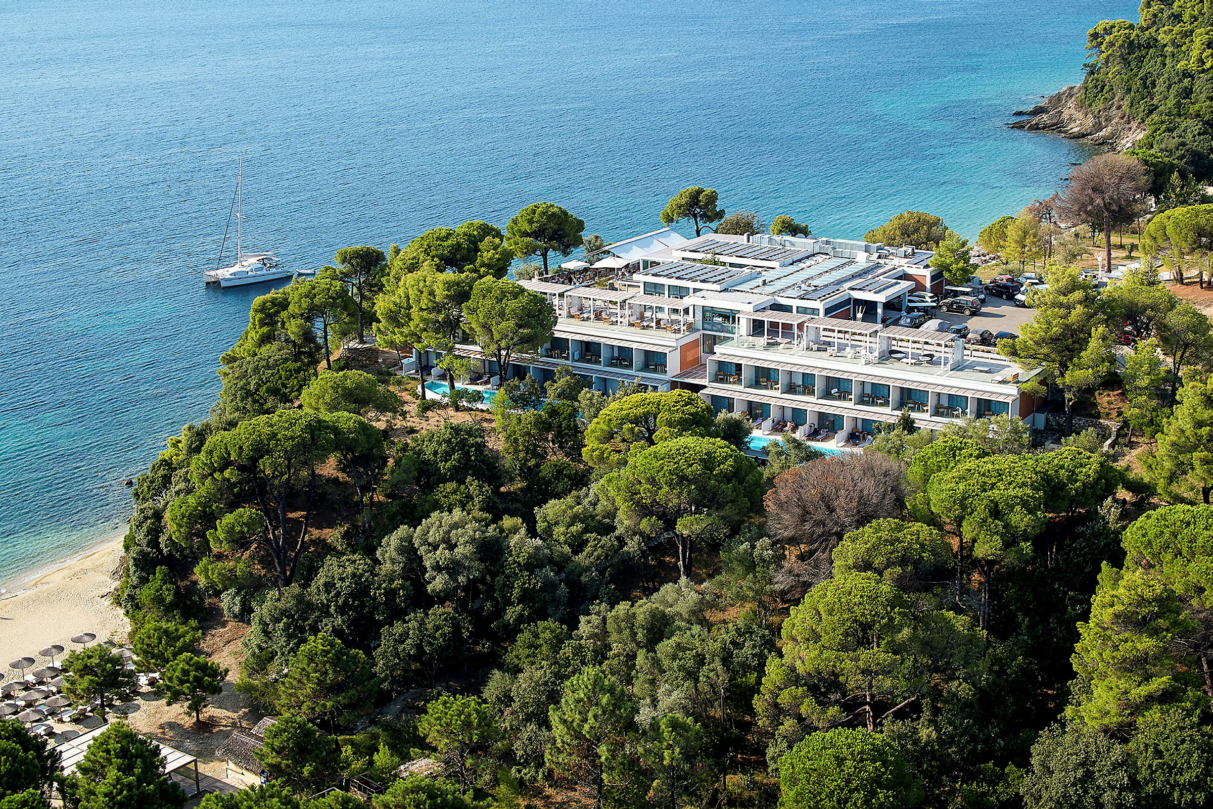 Ett hotell omgivet av grönska med stranden och havet bredvid. (AI-genererad text)