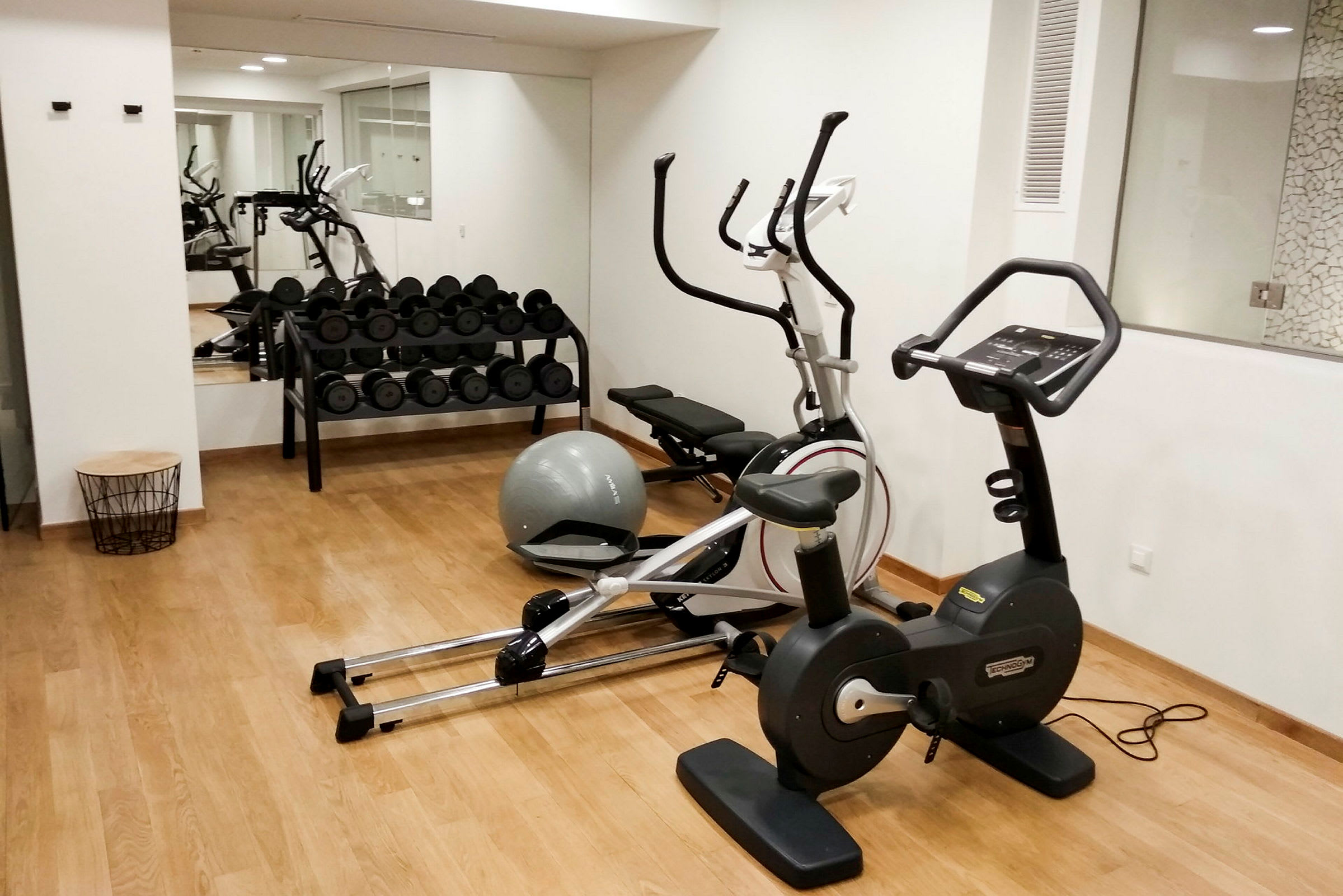 Ett gymrum med träningsutrustning som motionscykel, vikter och balansboll. (AI-genererad text)