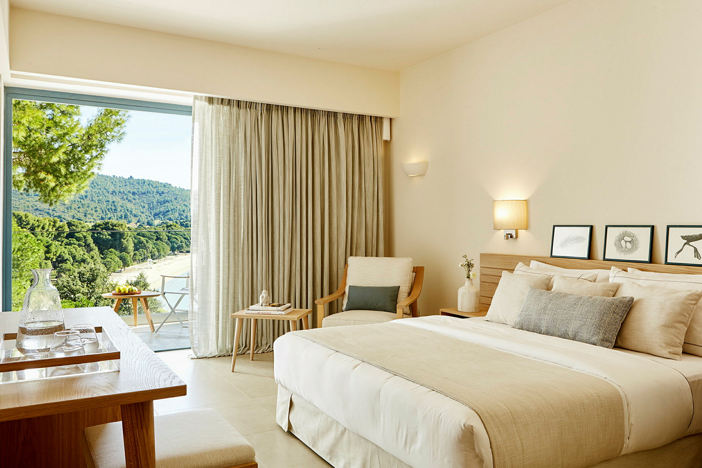 Ett hotellrum med en dubbelsäng, sittmöbler och ett stort fönster som erbjuder utsikt över en grönskande landskap. (AI-genererad text)
