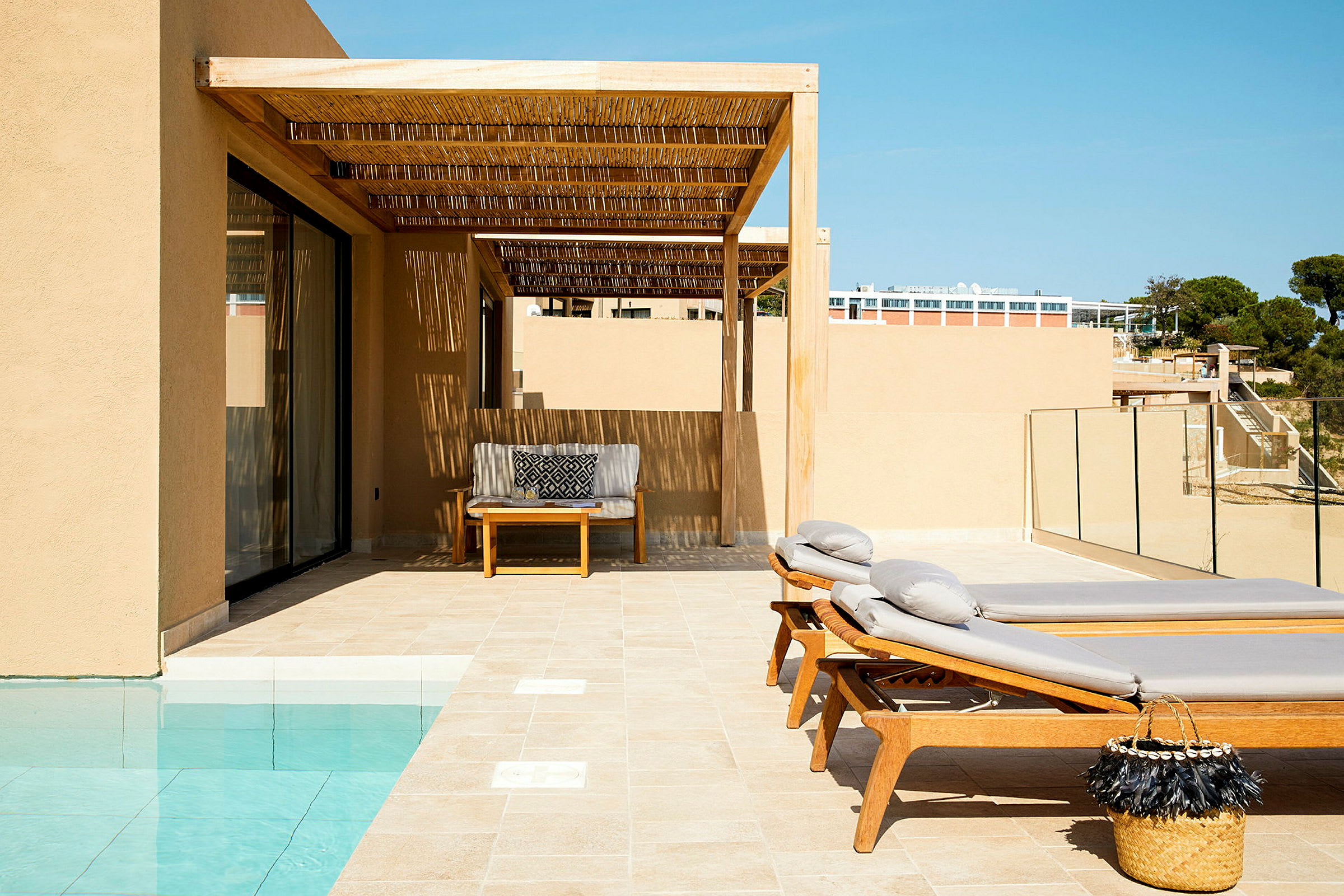 Soldränkt terrass med solstolar, bord och sittmöbler vid pool. (AI-genererad text)