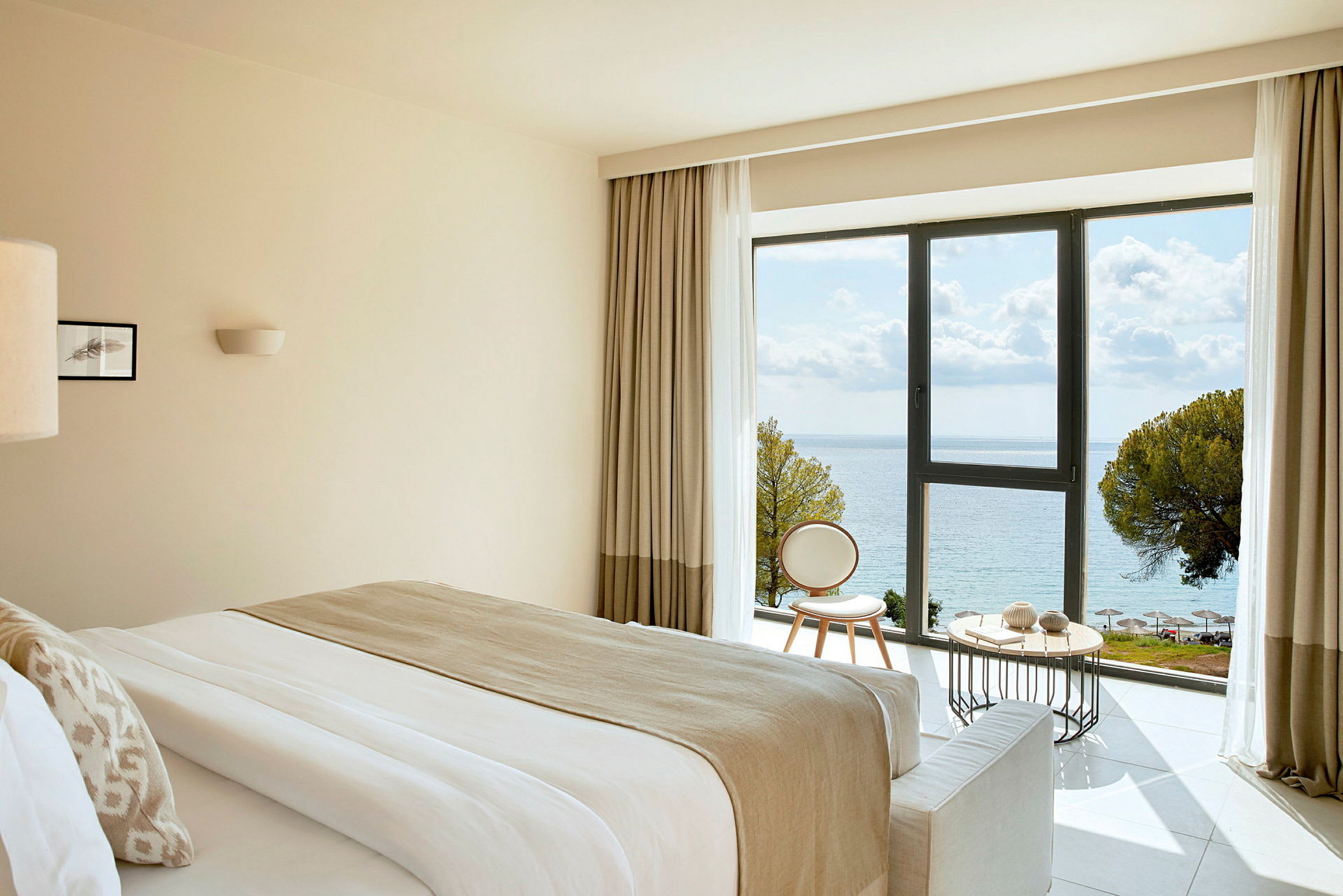 Hotellrum med havsutsikt genom ett stort fönster. (AI-genererad text)