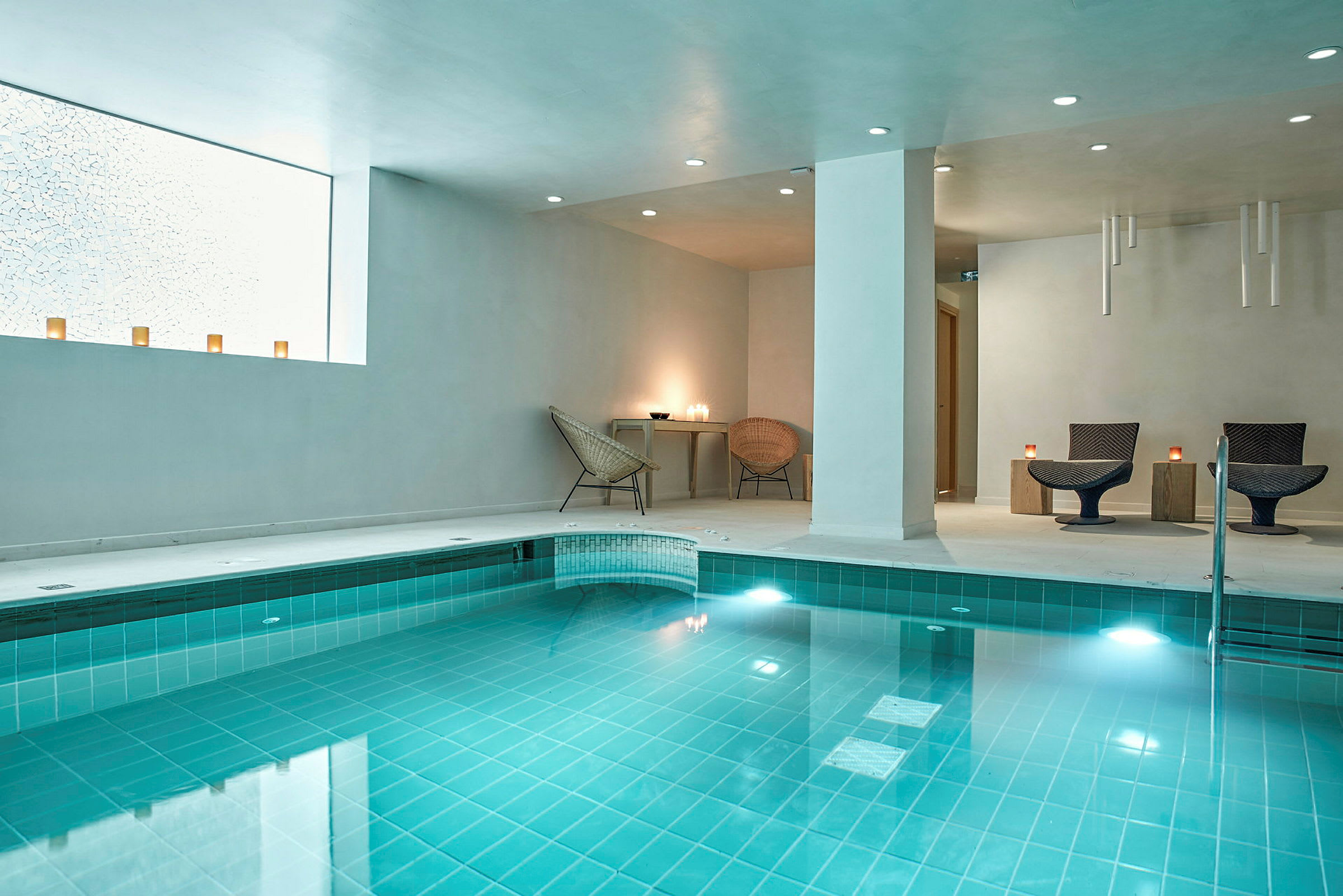 Inomhuspool med turkost vatten och moderna sittplatser. (AI-genererad text)