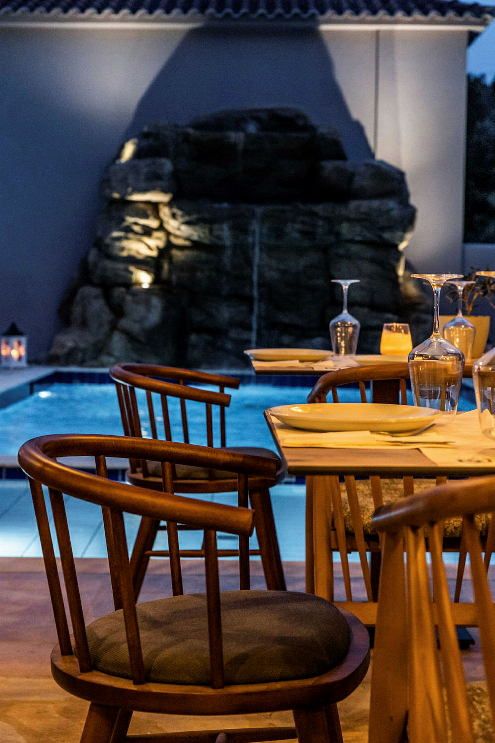 Uteservering med trästolar, bord och pool i bakgrunden. (AI-genererad text)