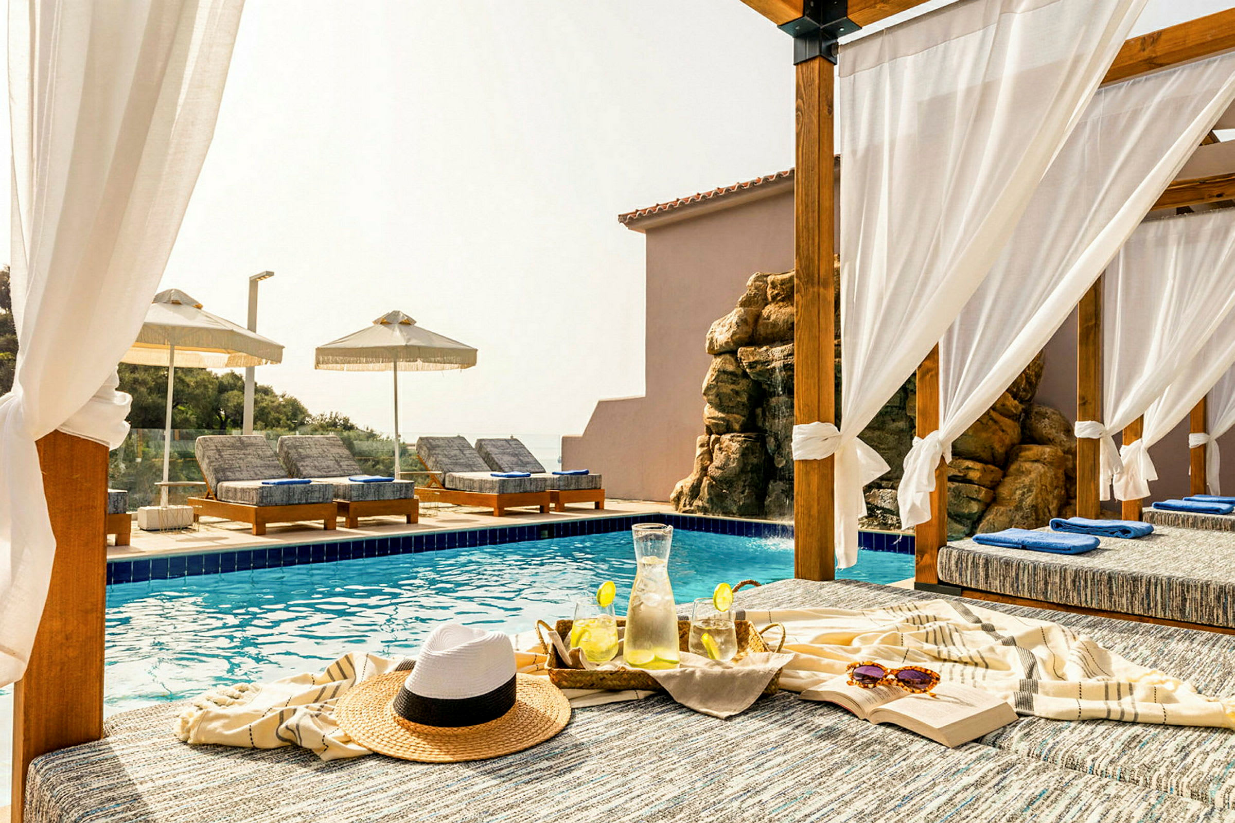 Privat pergola vid en pool med solstolar och serverad kyld citronvatten. (AI-genererad text)