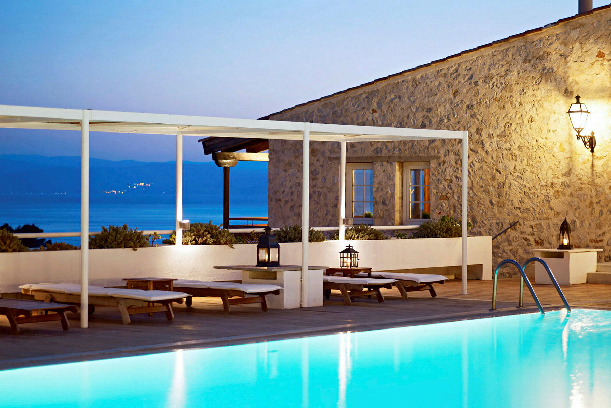 Lyxig villa med pool framför havsutsikt och solstolar. (AI-genererad text)
