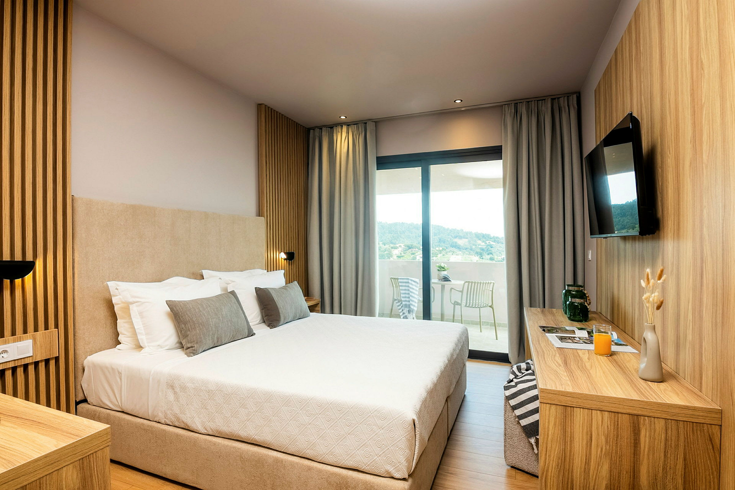 Hotellrum med en stor säng, modern inredning och utsikt mot en terrass. (AI-genererad text)
