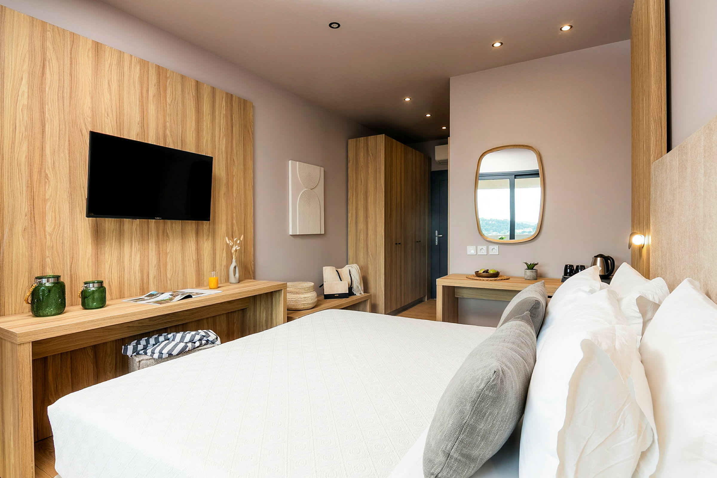 Ett modernt hotellrum med en dubbelsäng, träinredning, bord med spegel och TV. (AI-genererad text)