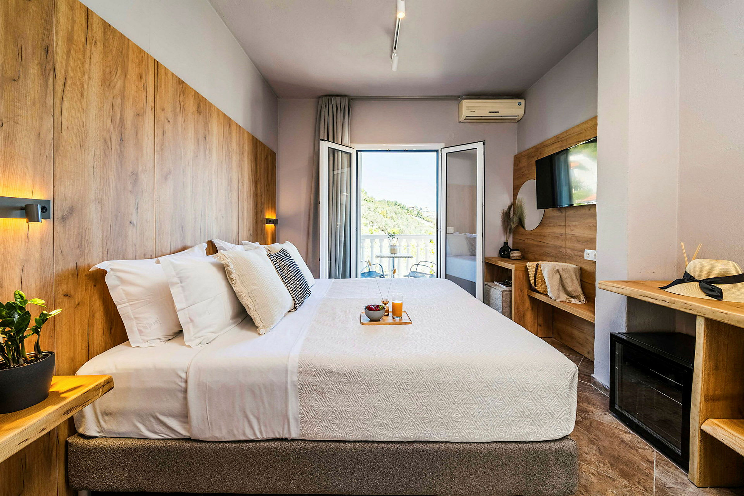 Hotellrum med en dubbelsäng, utsmyckat med träpaneler och en balkong med utsikt. (AI-genererad text)