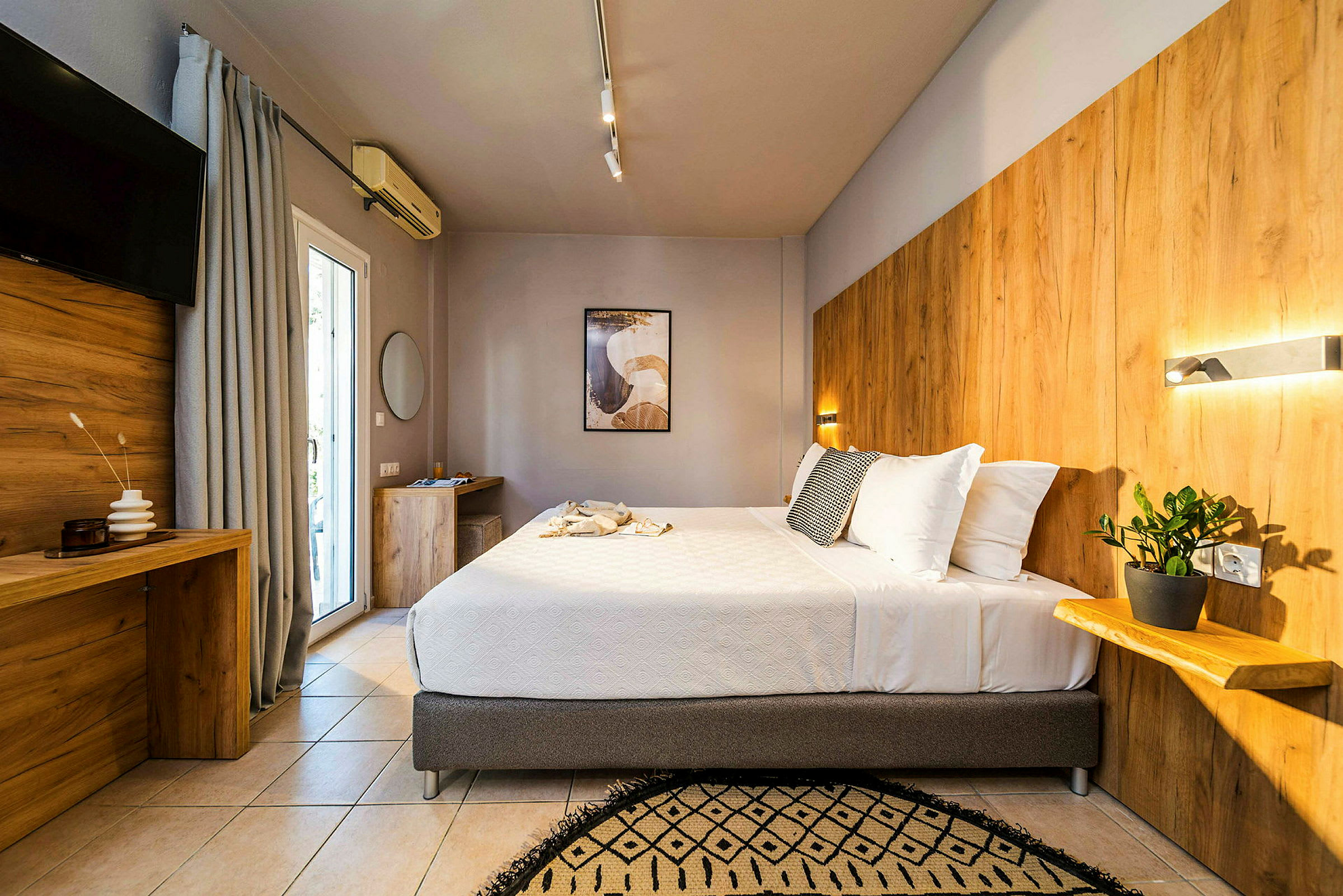 Ett modernt hotellrum med en stor säng, träpaneler på väggen och en växt på en hylla. (AI-genererad text)