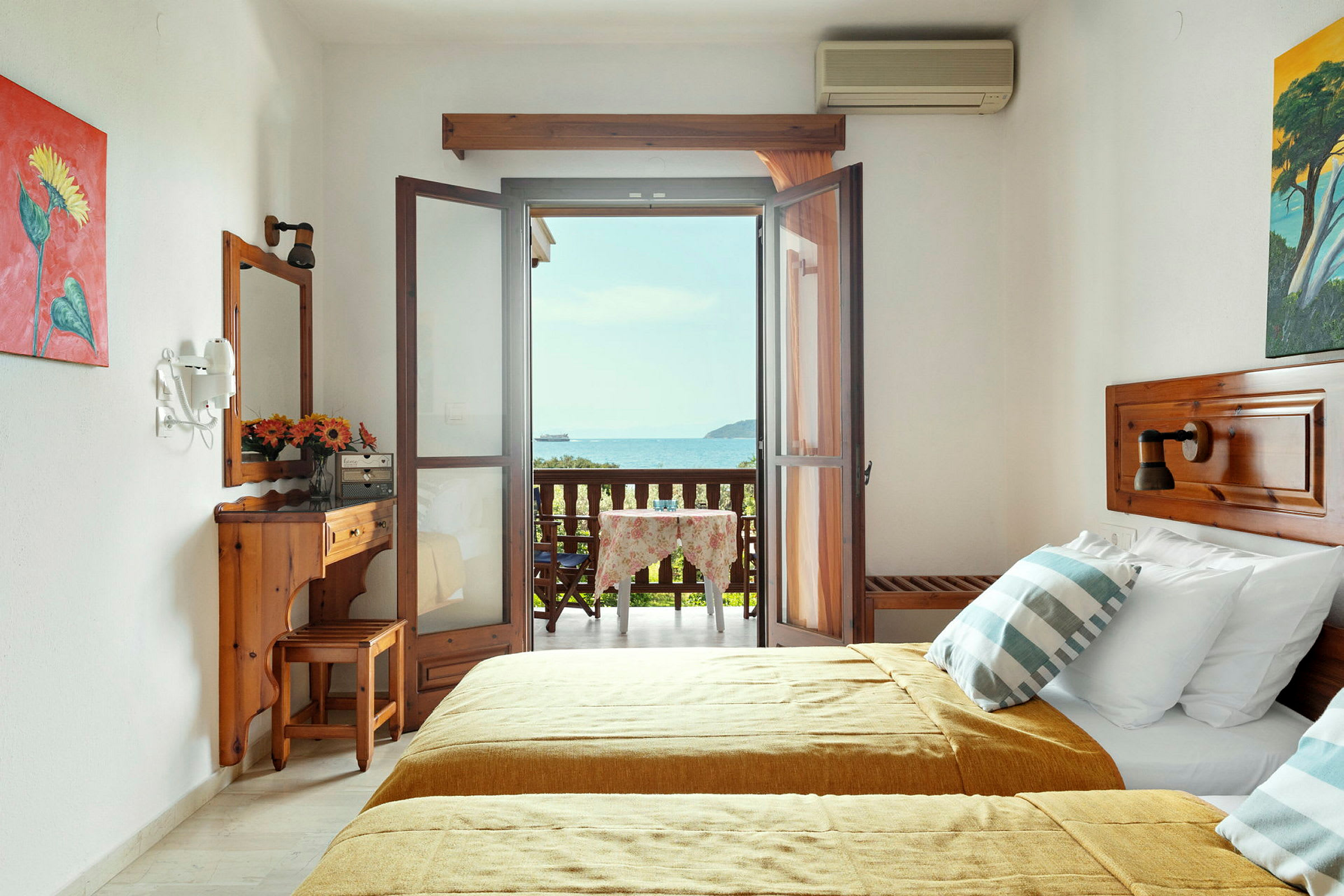 Ett hotellrum med två sängar och en möblerad balkong med utsikt över havet. (AI-genererad text)