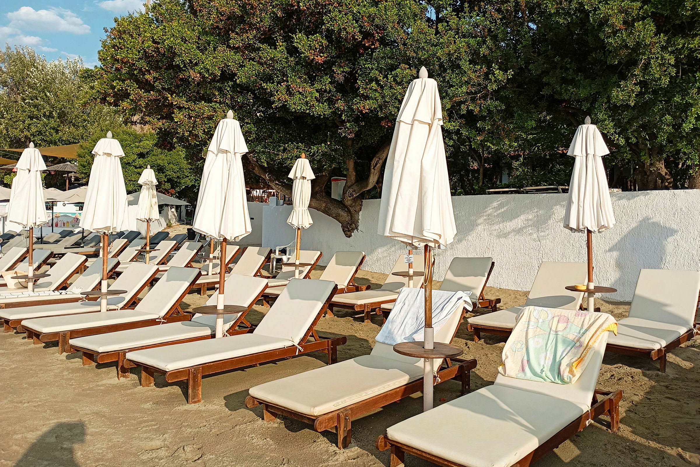Solstolar med parasoller står på sandstrand. (AI-genererad text)