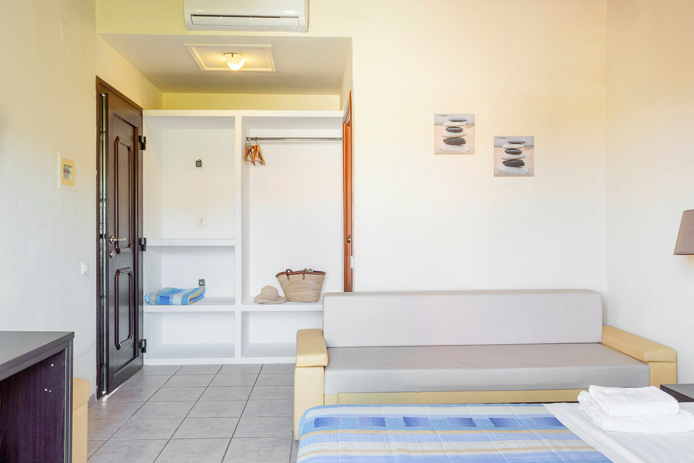 En hotellrum med soffa, öppen garderob, och säng. (AI-genererad text)