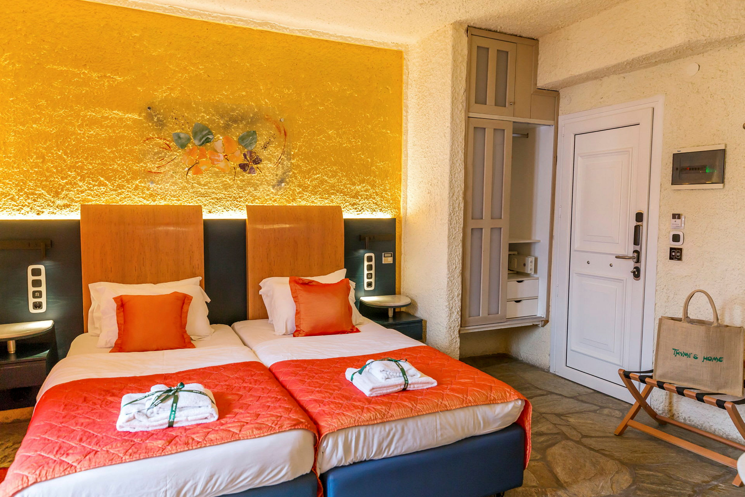 Två enkelsängar med orange överkast i ett hotellrum. (AI-genererad text)