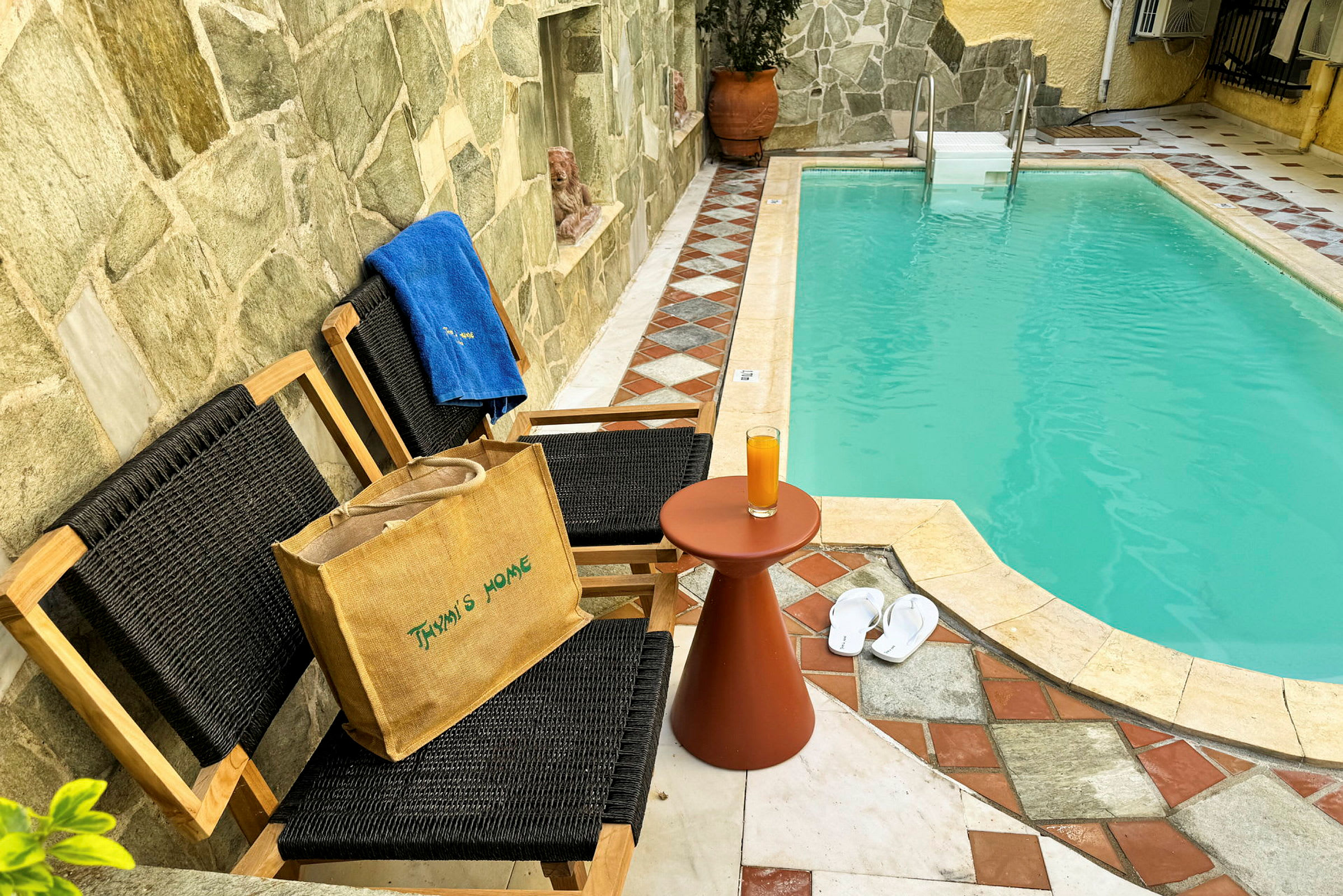 En pool med två stolar och ett bord, samt tofflor och en handduk bredvid. (AI-genererad text)