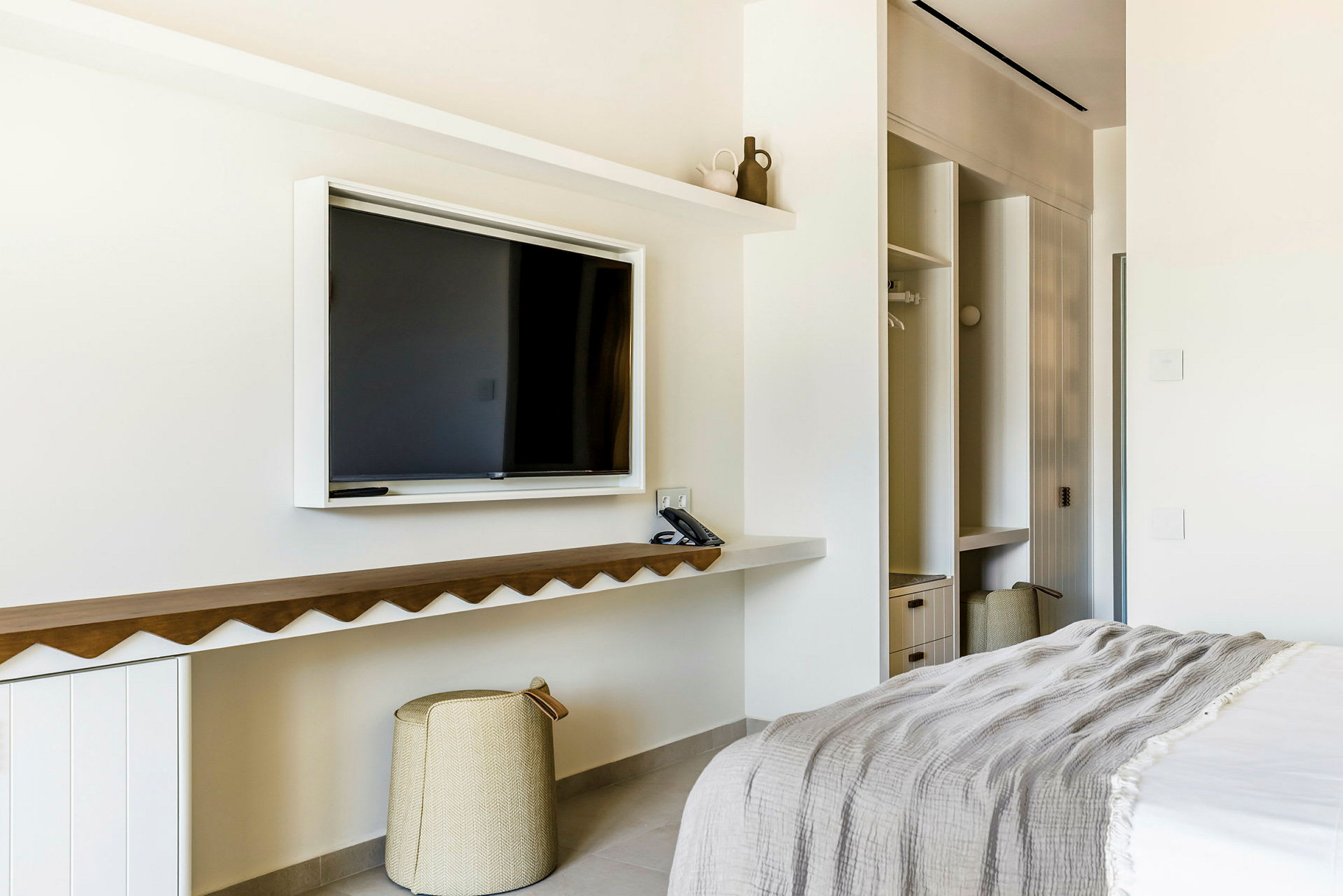 Hotellrum med TV, säng och förvaringsutrymmen. (AI-genererad text)