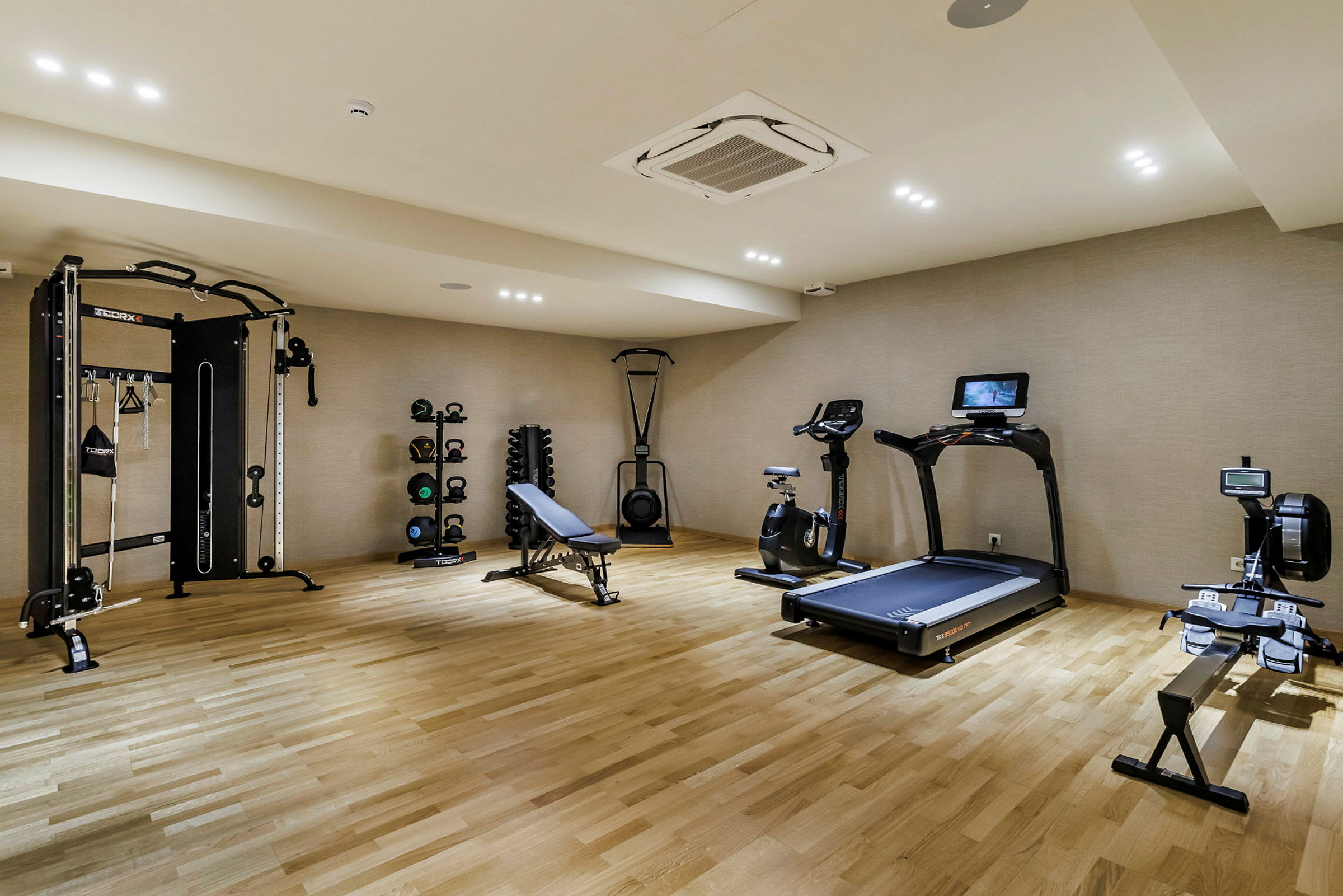 Ett gym med träningsmaskiner som löpband, cykel och roddmaskin samt träningsbänk. (AI-genererad text)