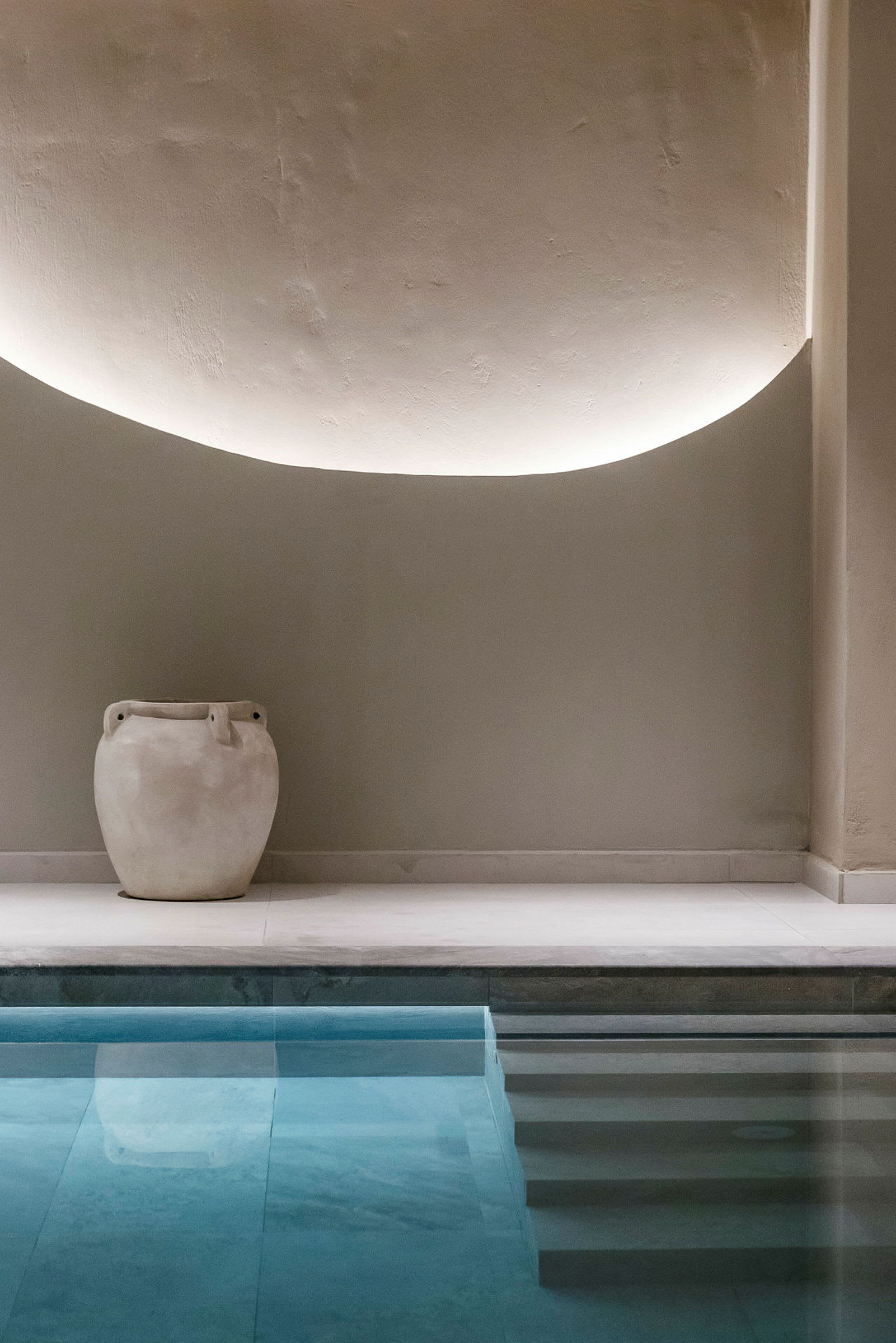 En vit kruka står på golvet vid sidan av en swimmingpool. (AI-genererad text)