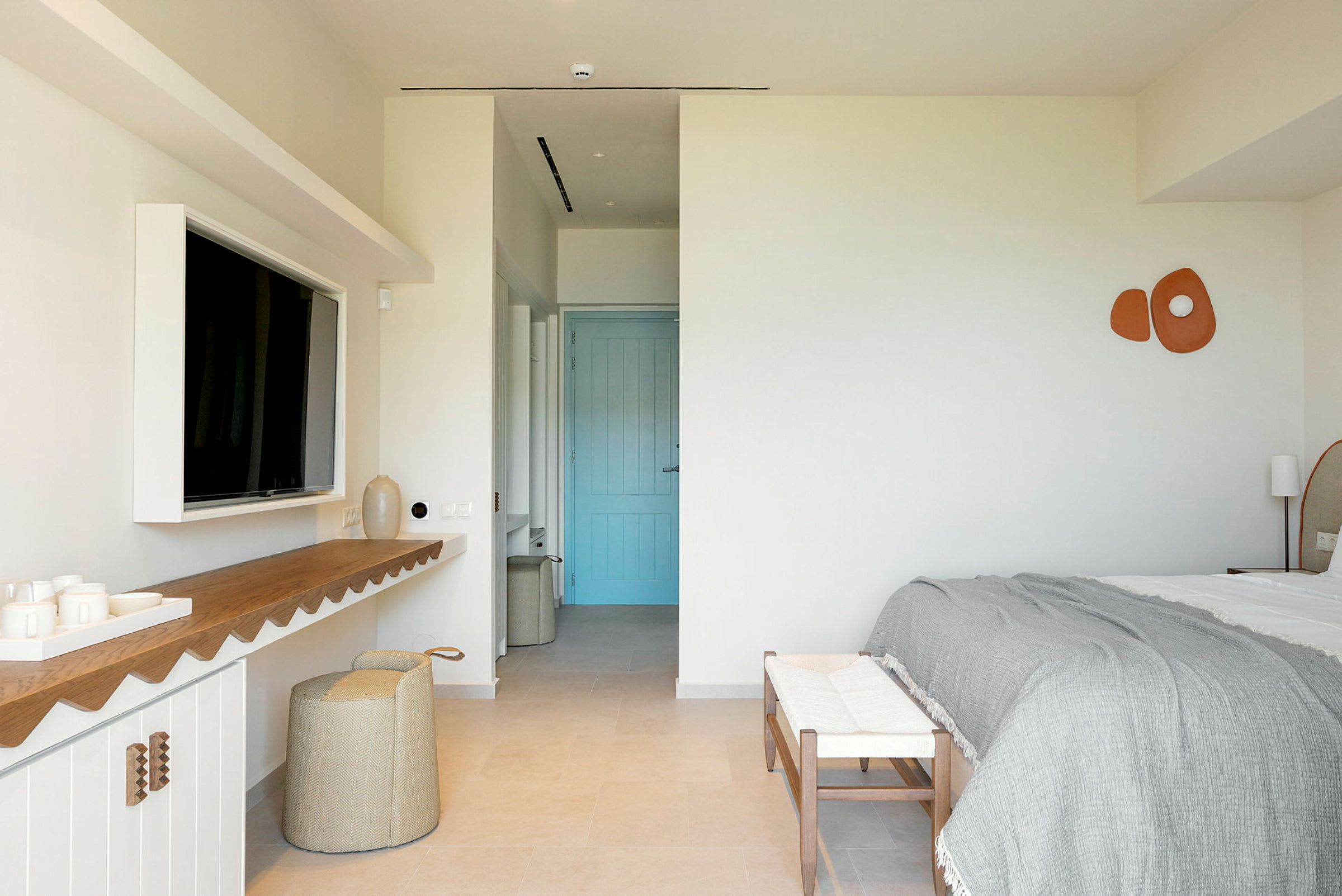 Ett modernt hotellrum med dubbelsäng, en blå dörr, och minimalistisk inredning. (AI-genererad text)