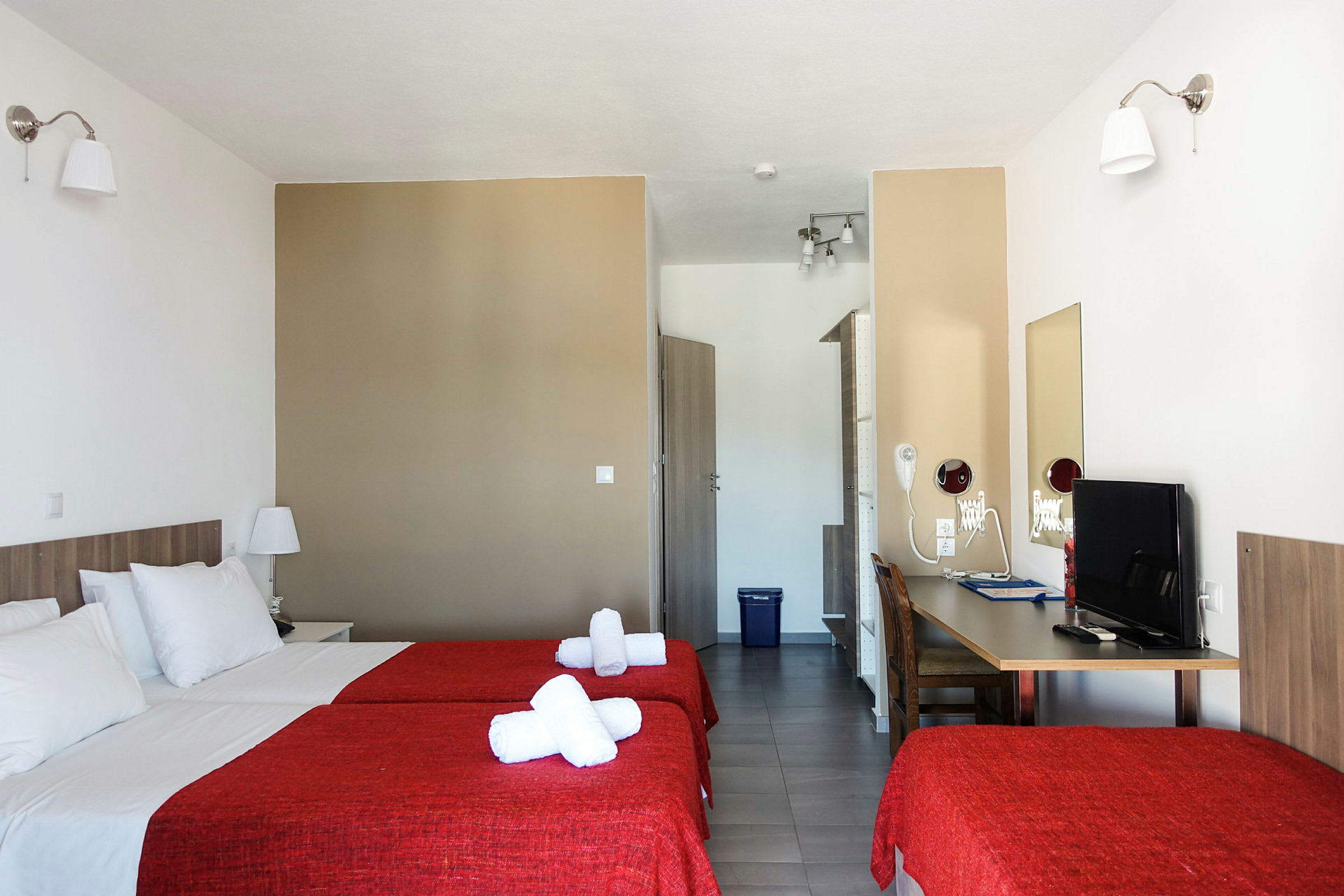 Hotellrum med två bäddar och röda överkast. (AI-genererad text)