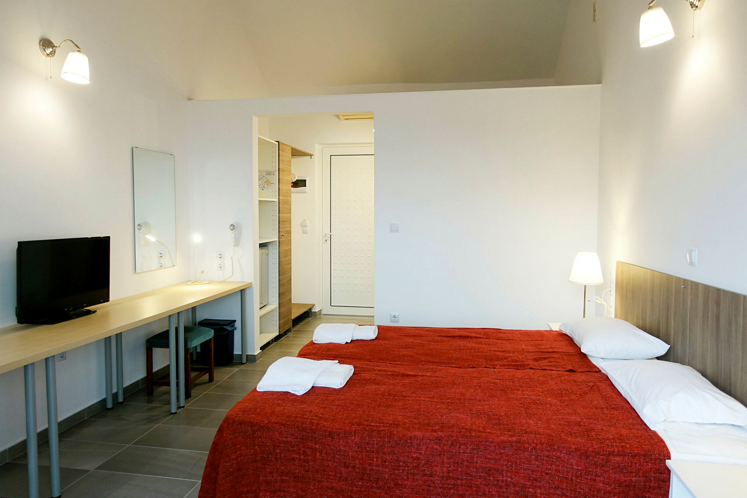 Ett hotellrum med två enkelsängar, en lång arbetsyta, en TV och en dörr till en garderob. (AI-genererad text)