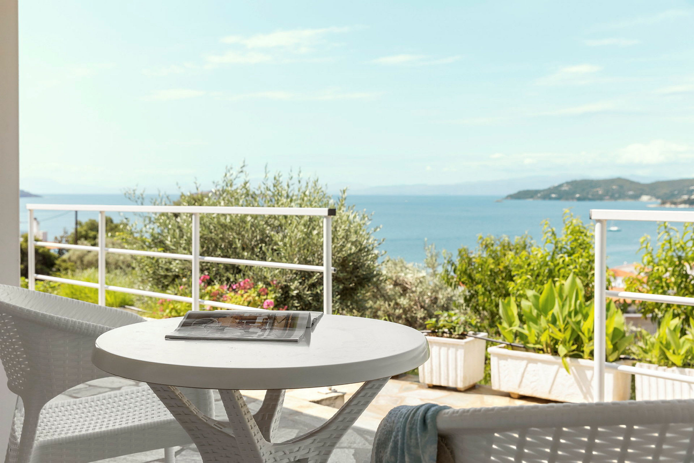 Utsikt över havet från en terrass med ett bord och stolar. (AI-genererad text)