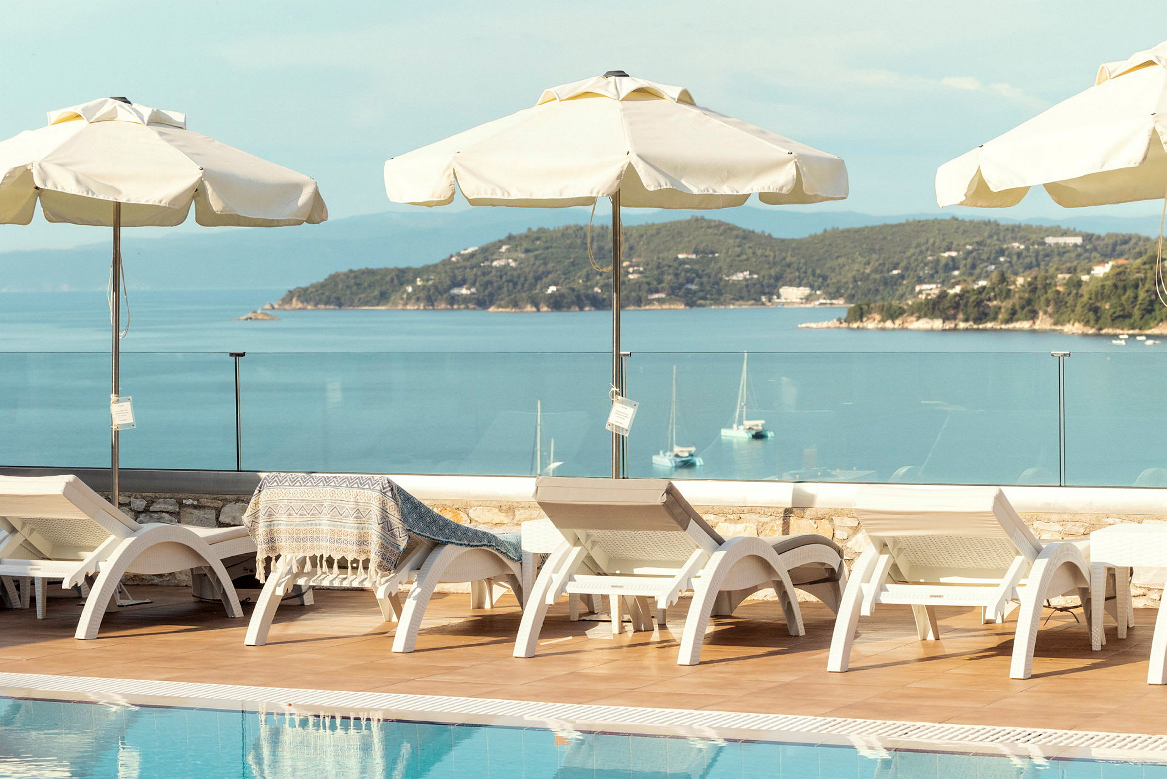 Sunloungers och parasoller vid en pool med havsutsikt. (AI-genererad text)