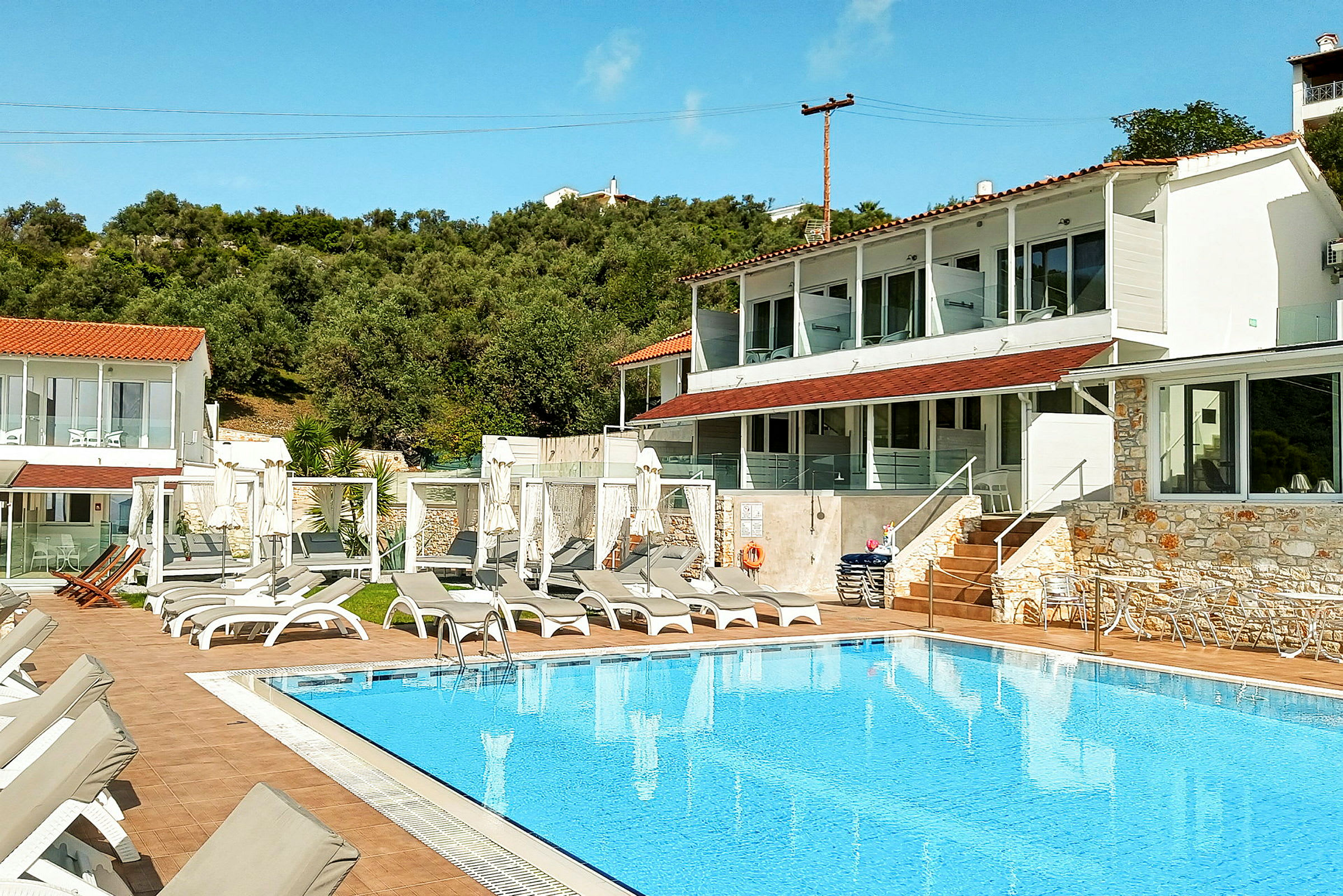 Poolområde med solstolar framför en hotellbyggnad. (AI-genererad text)