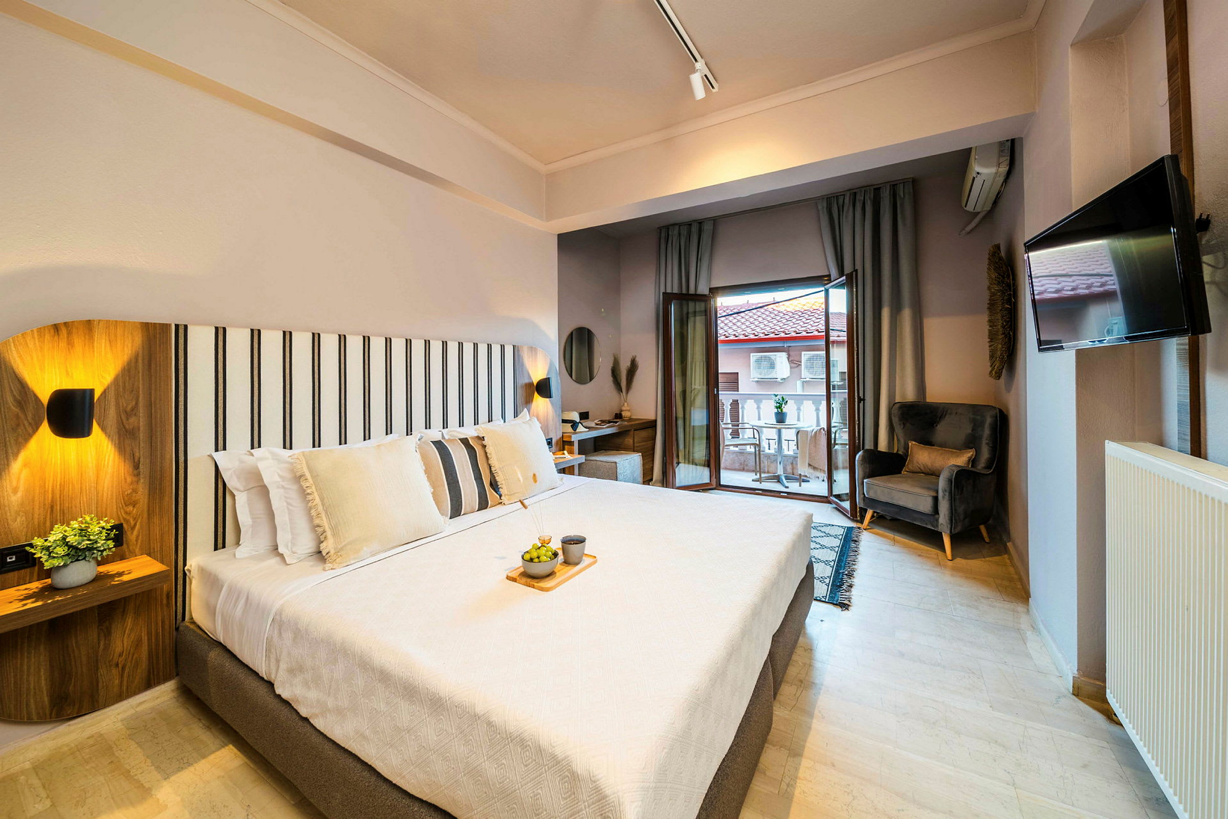 Ett ljust och modernt hotellrum med en stor säng, sittplats och balkong. (AI-genererad text)