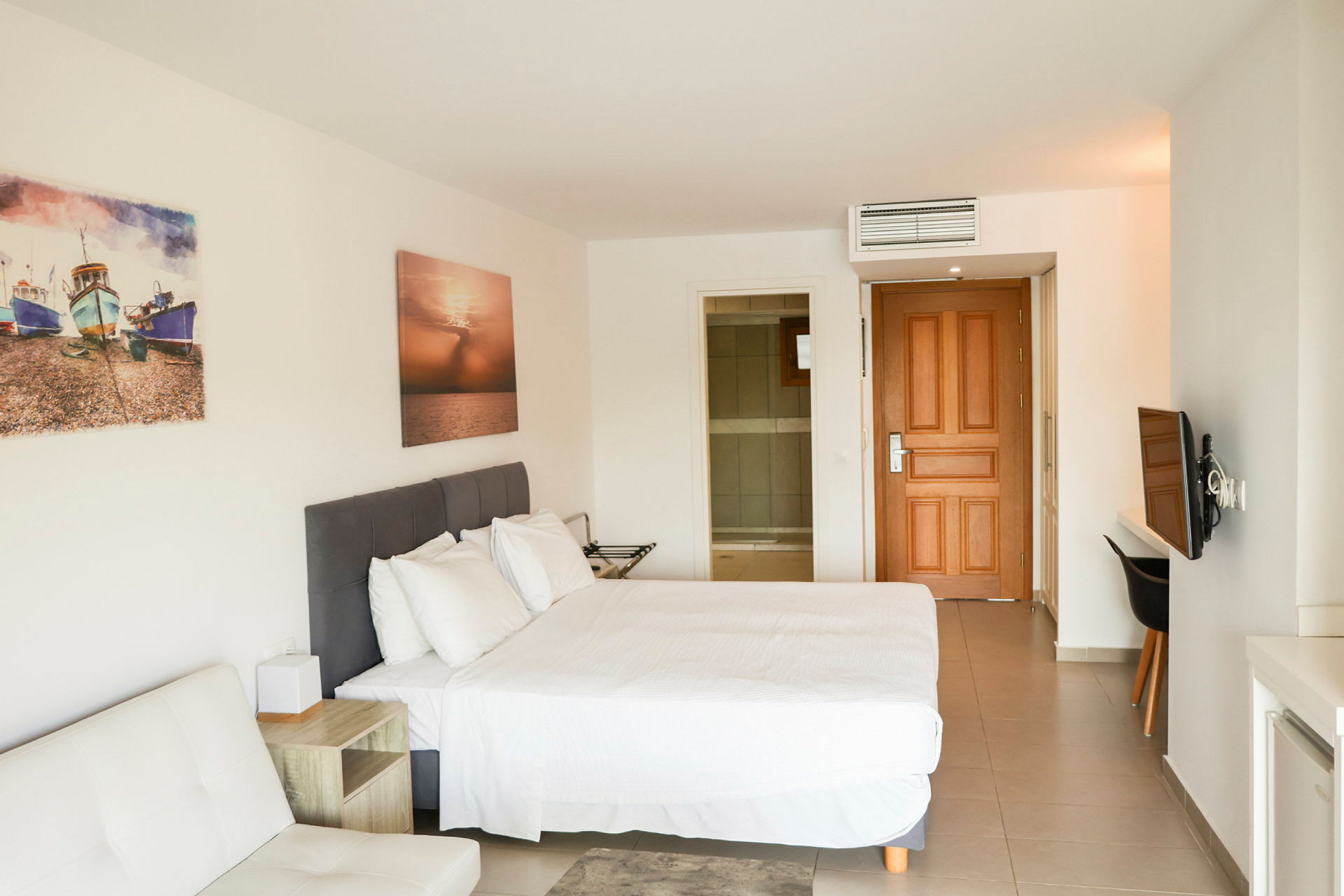 Hotellrum med en säng, väggkonst och dörr. (AI-genererad text)