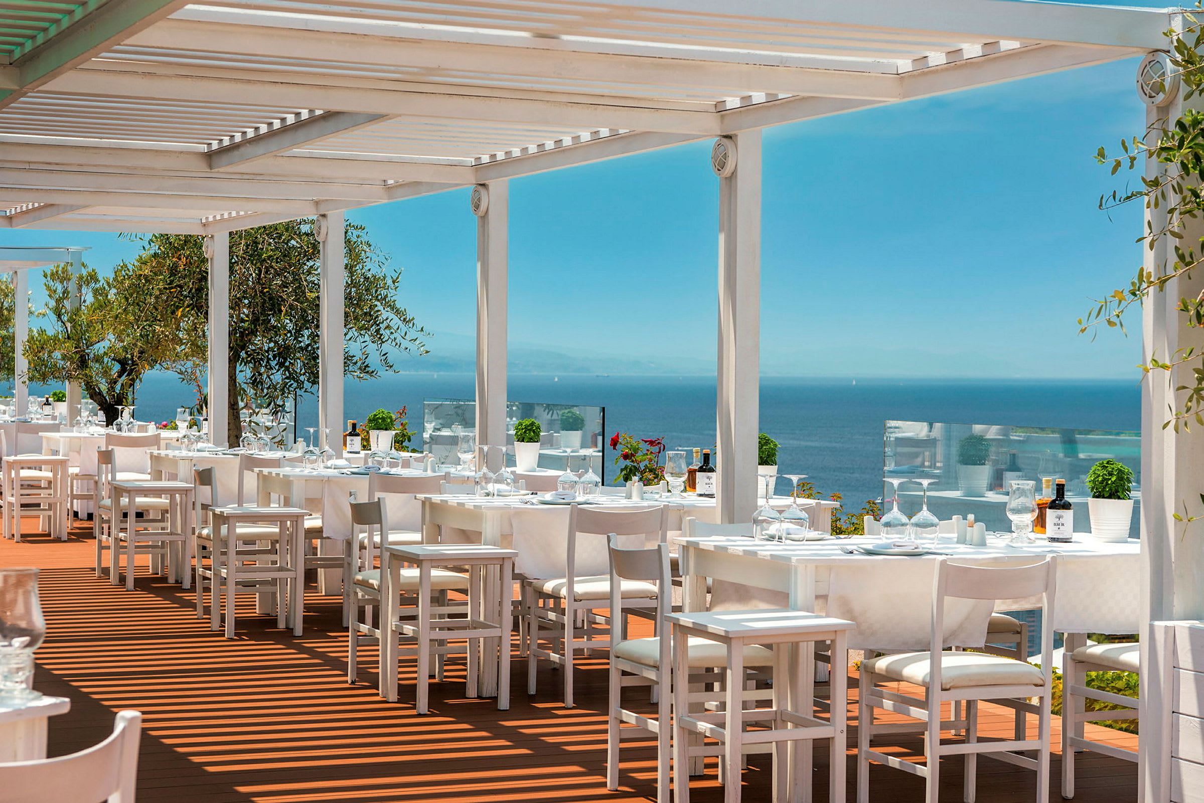 Utomhusrestaurang med vita möbler och utsikt över havet. (AI-genererad text)