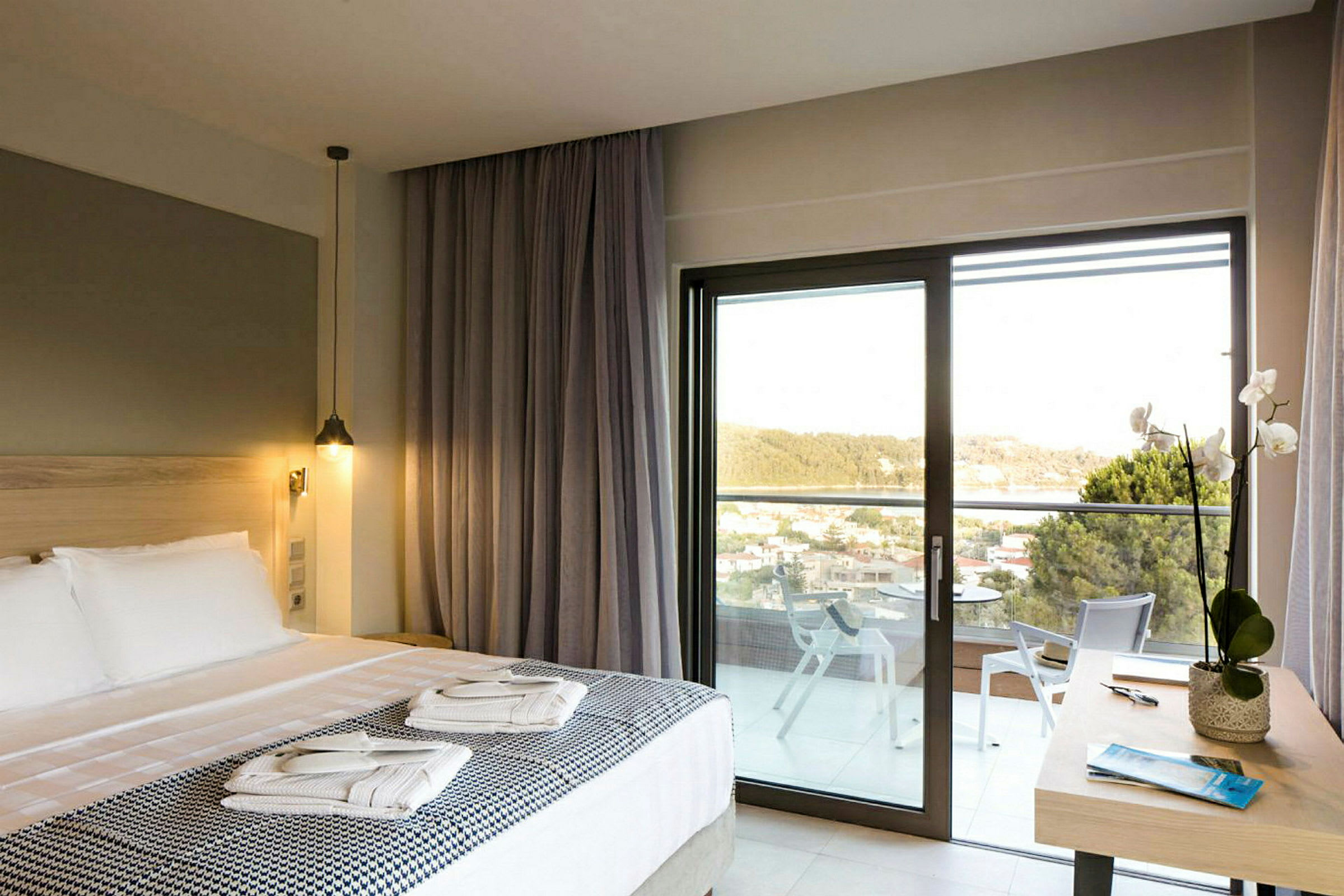 Hotellrum med dubbelsäng, balkong och utsikt över grönska. (AI-genererad text)