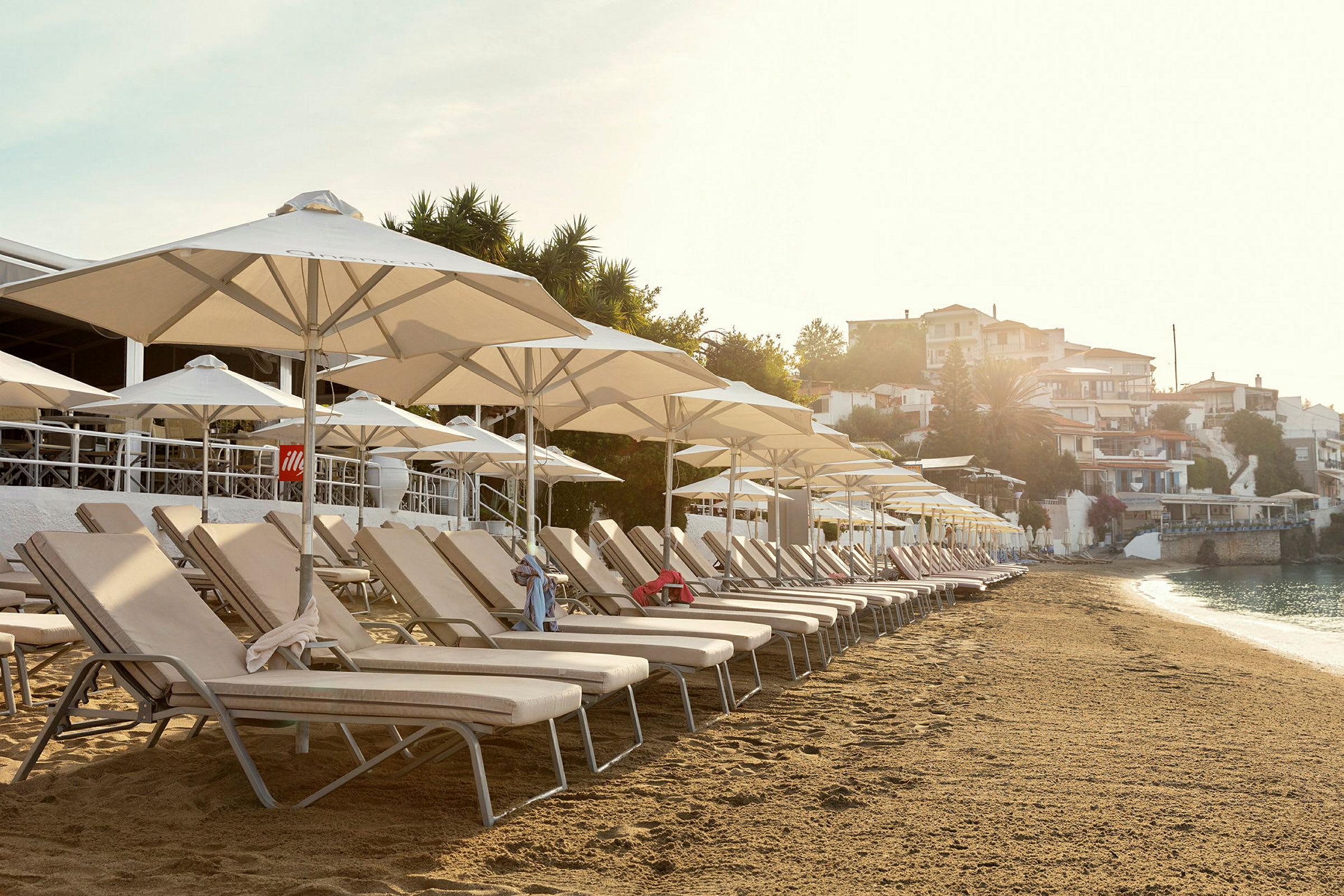 Solstolar med parasoller på en sandstrand vid havet. (AI-genererad text)