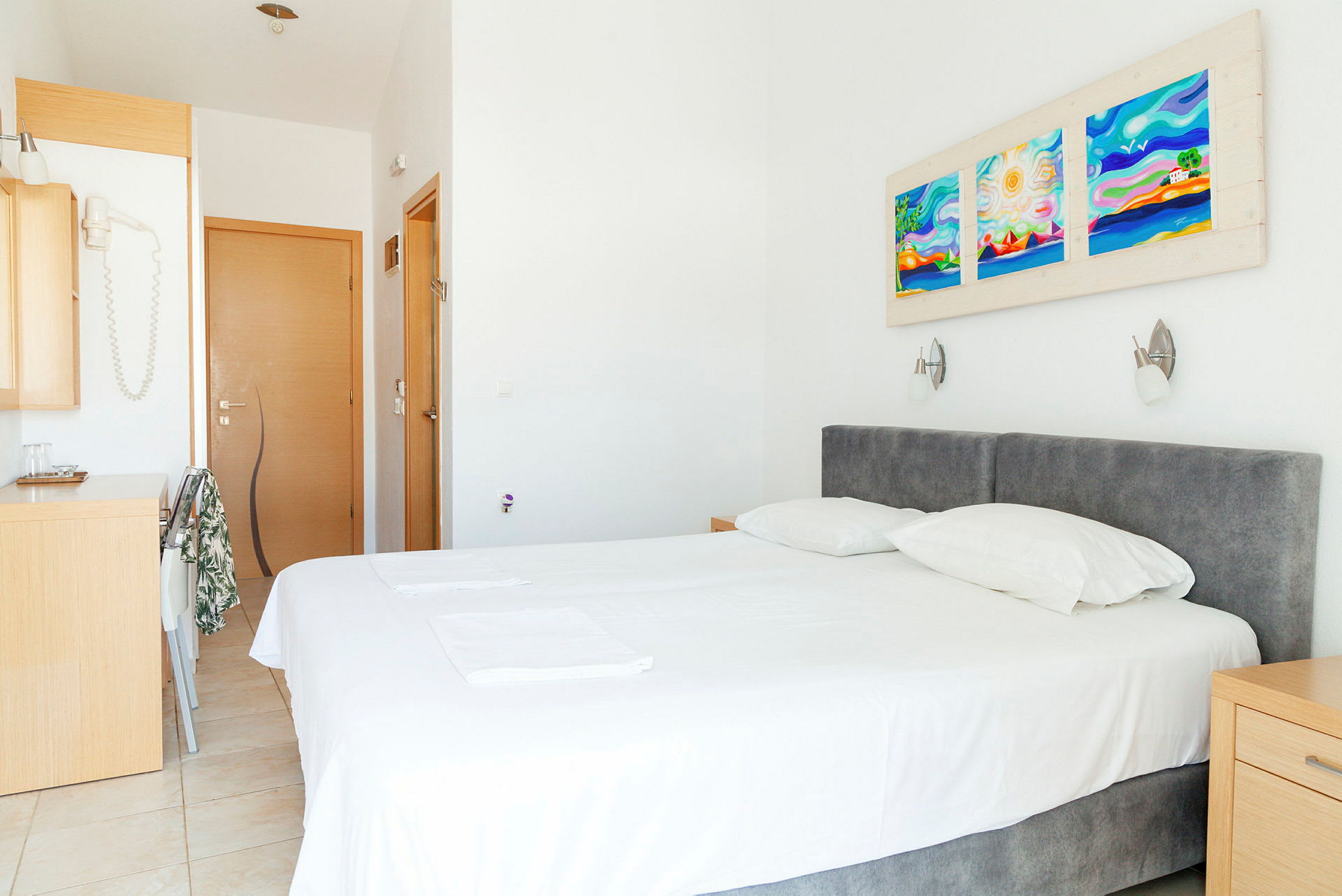Ett hotellrum med en säng, två kuddar och dekorationer på väggen. (AI-genererad text)
