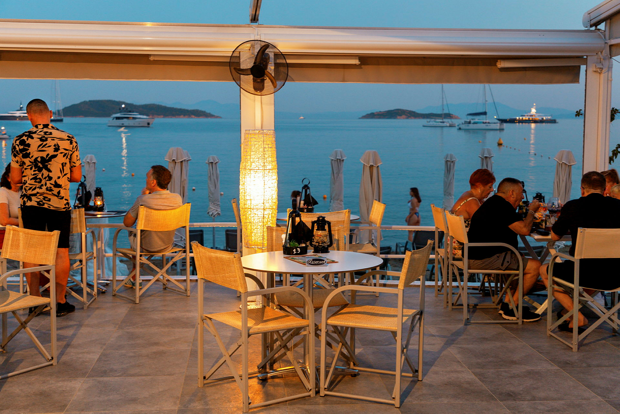 En restaurang med utsikt över havet och båtar vid solnedgången. (AI-genererad text)