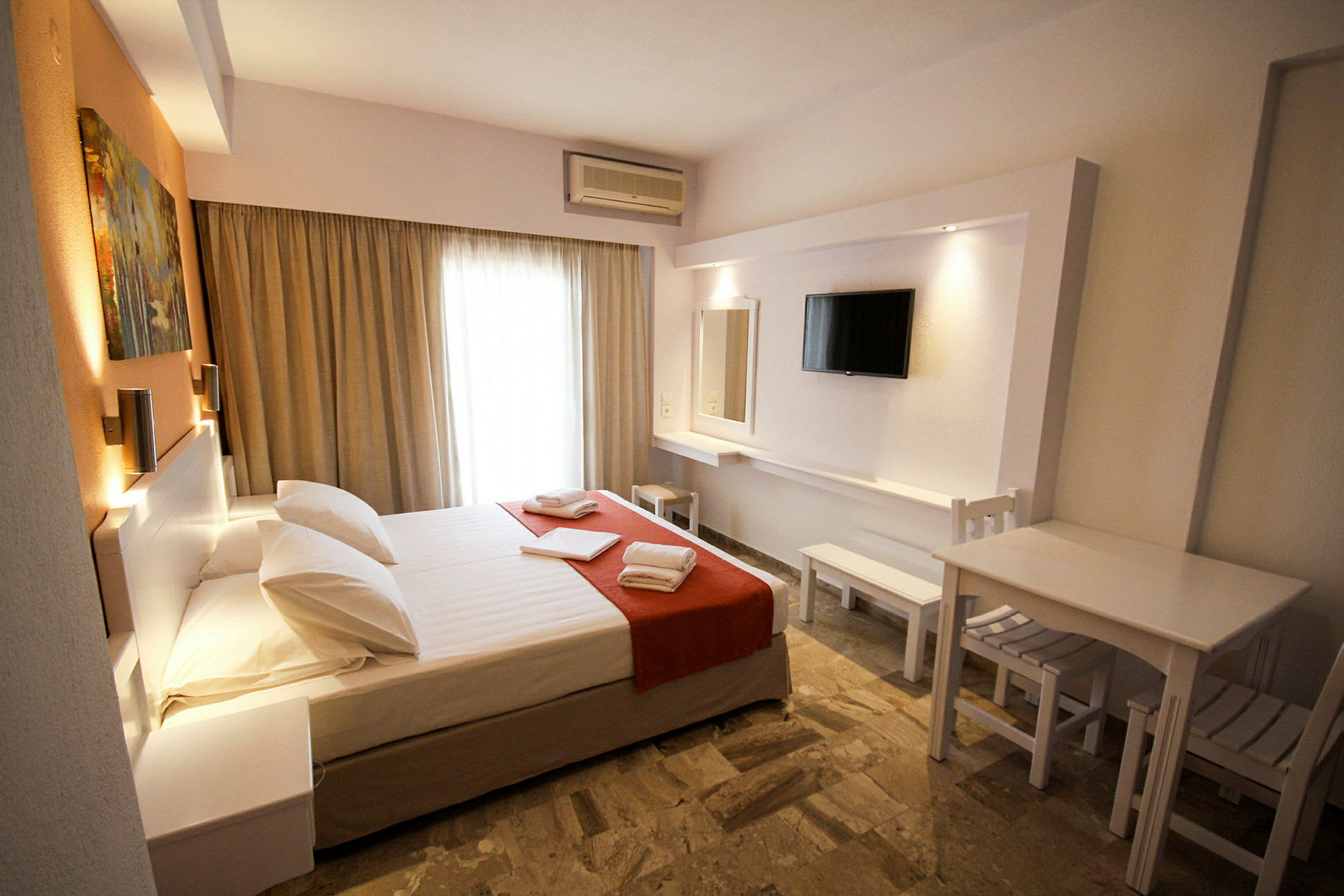 Ett hotellrum med en dubbelsäng, tv och sittmöbel. (AI-genererad text)