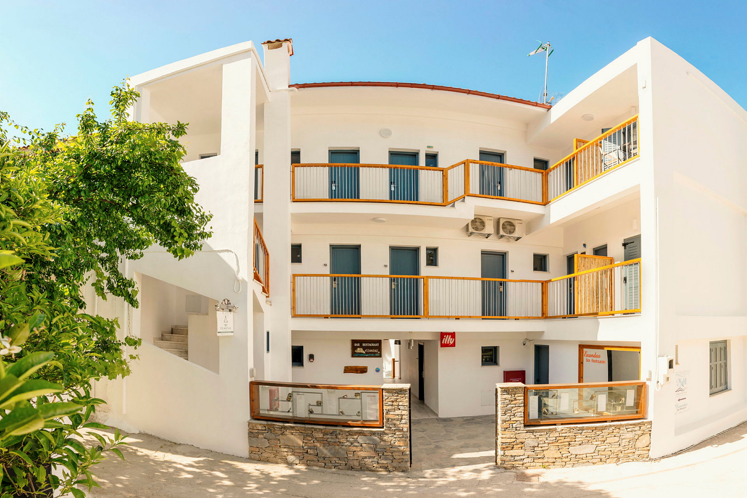 Ett boutiquehotell i medelhavsstil med vit fasad och trädetaljer. (AI-genererad text)