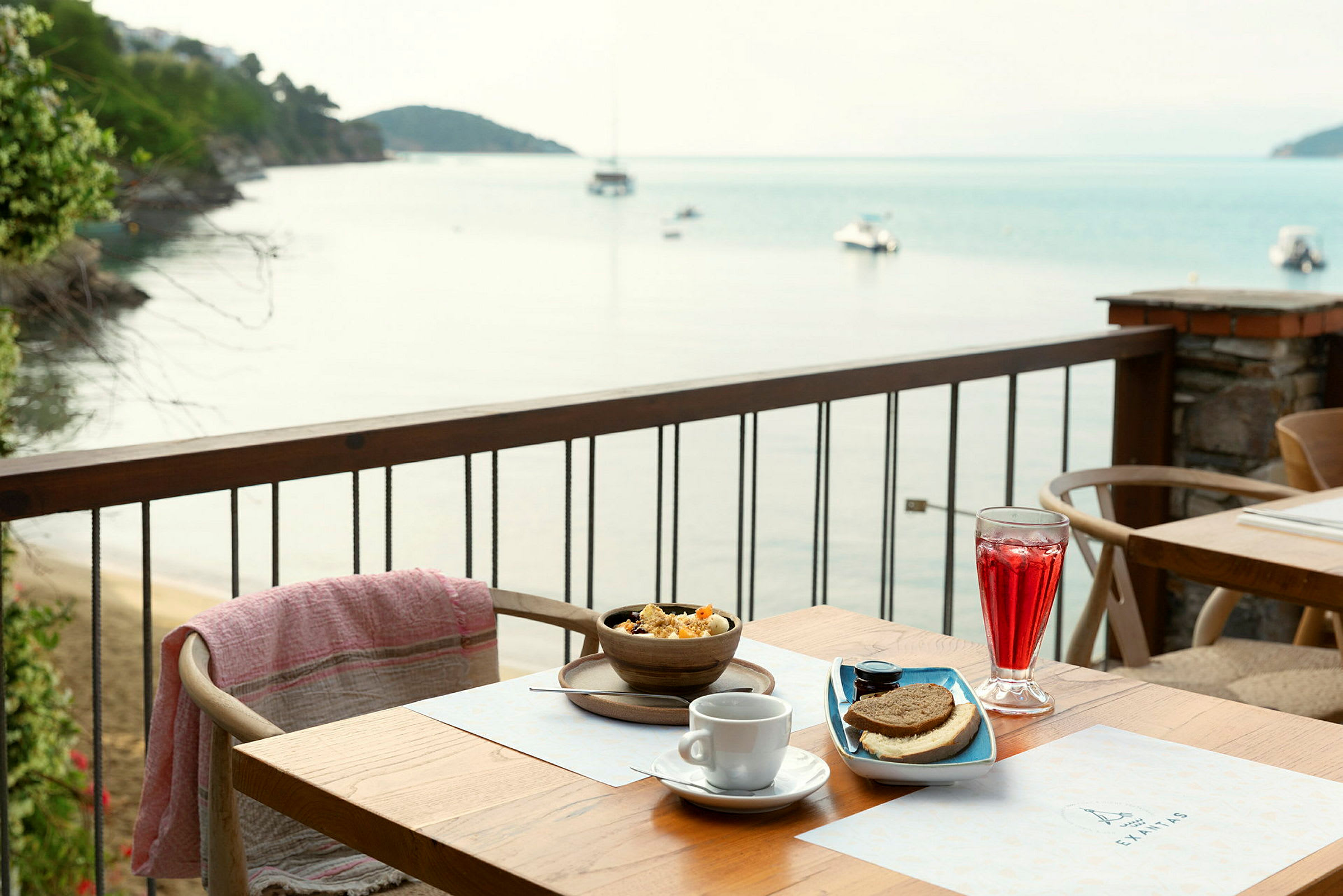 Frukost serverad på en terrass med utsikt över havet och båtar. (AI-genererad text)