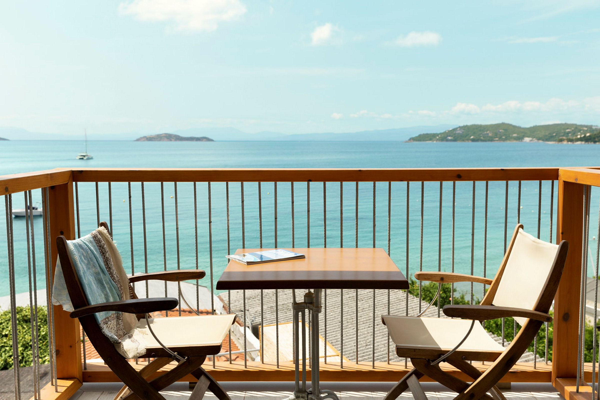 Utsikt från en balkong med två stolar, ett bord och havet i bakgrunden. (AI-genererad text)