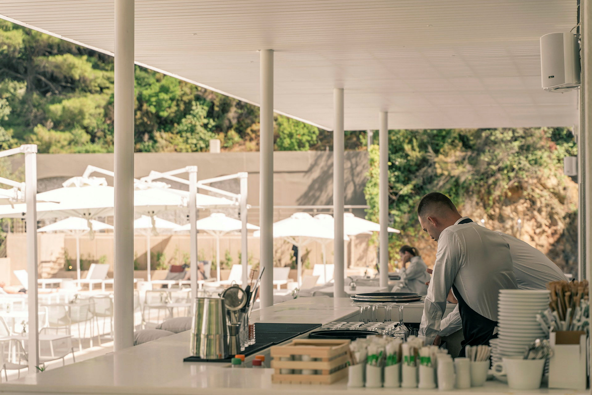 Serveringsområde utomhus med en bar och parasoller i bakgrunden. (AI-genererad text)