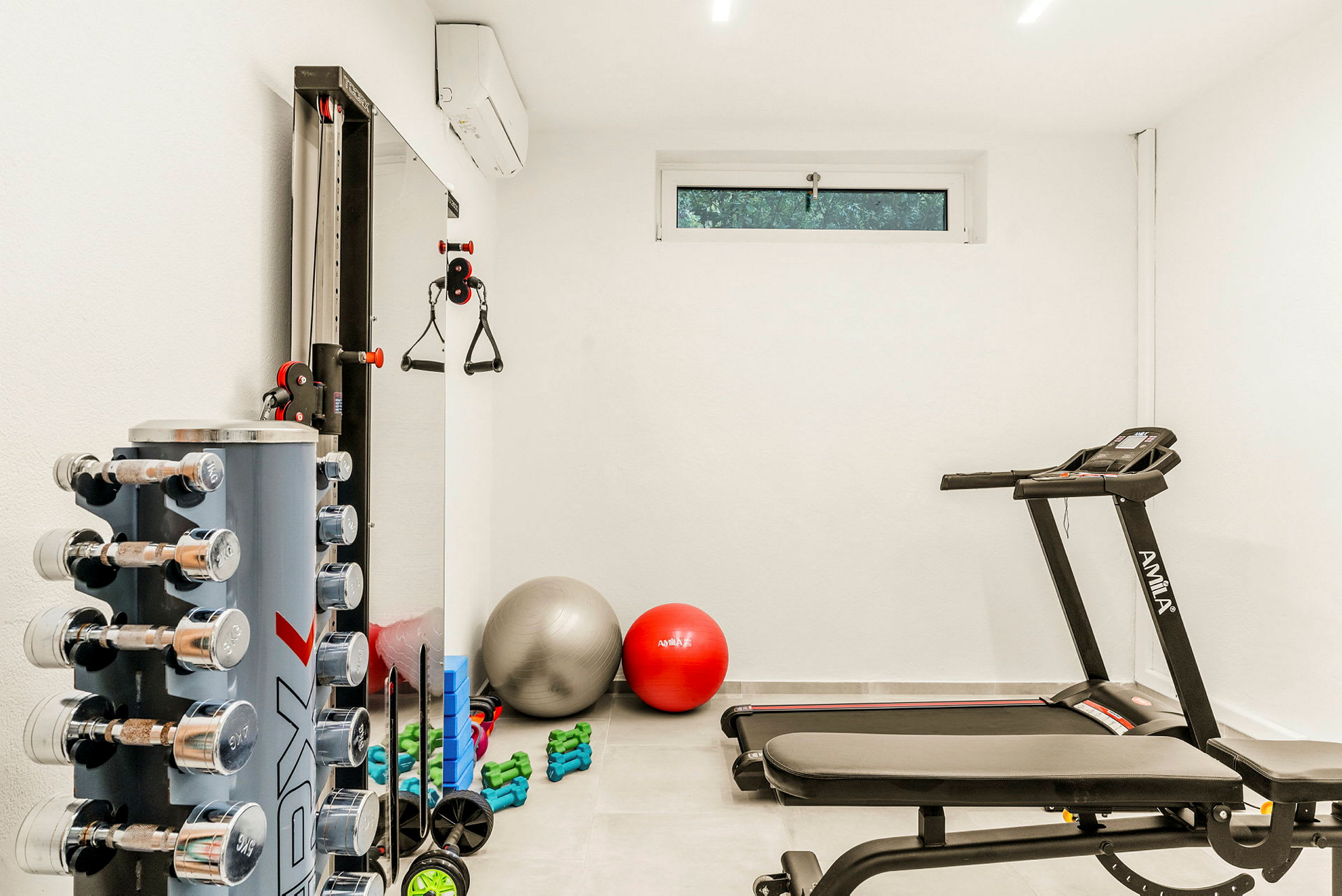 Ett gym med träningsutrustning, inklusive hantlar, yogabollar och ett löpband. (AI-genererad text)