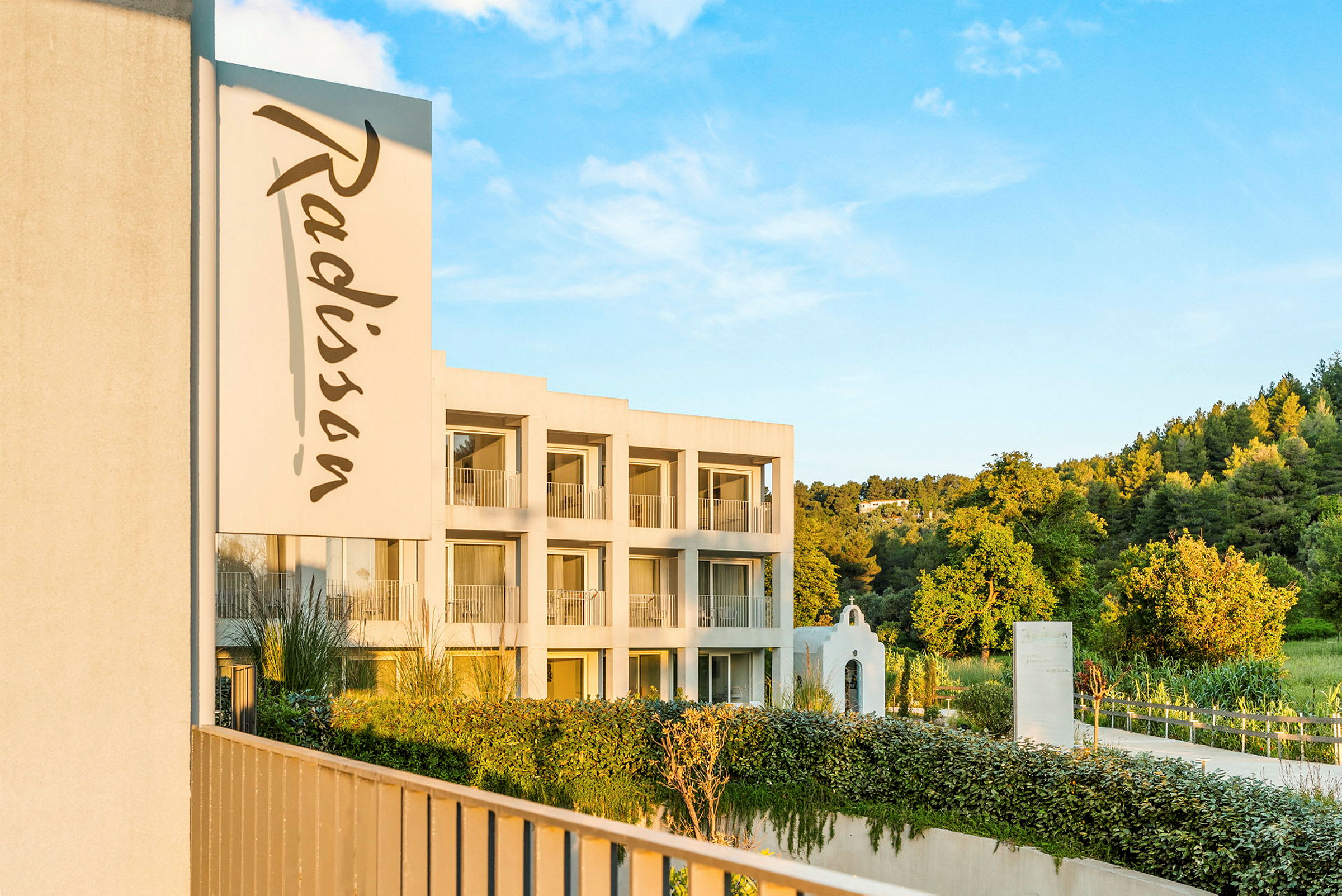 Bild av en byggnad med Radisson-logotypen och omgivande grönska. (AI-genererad text)