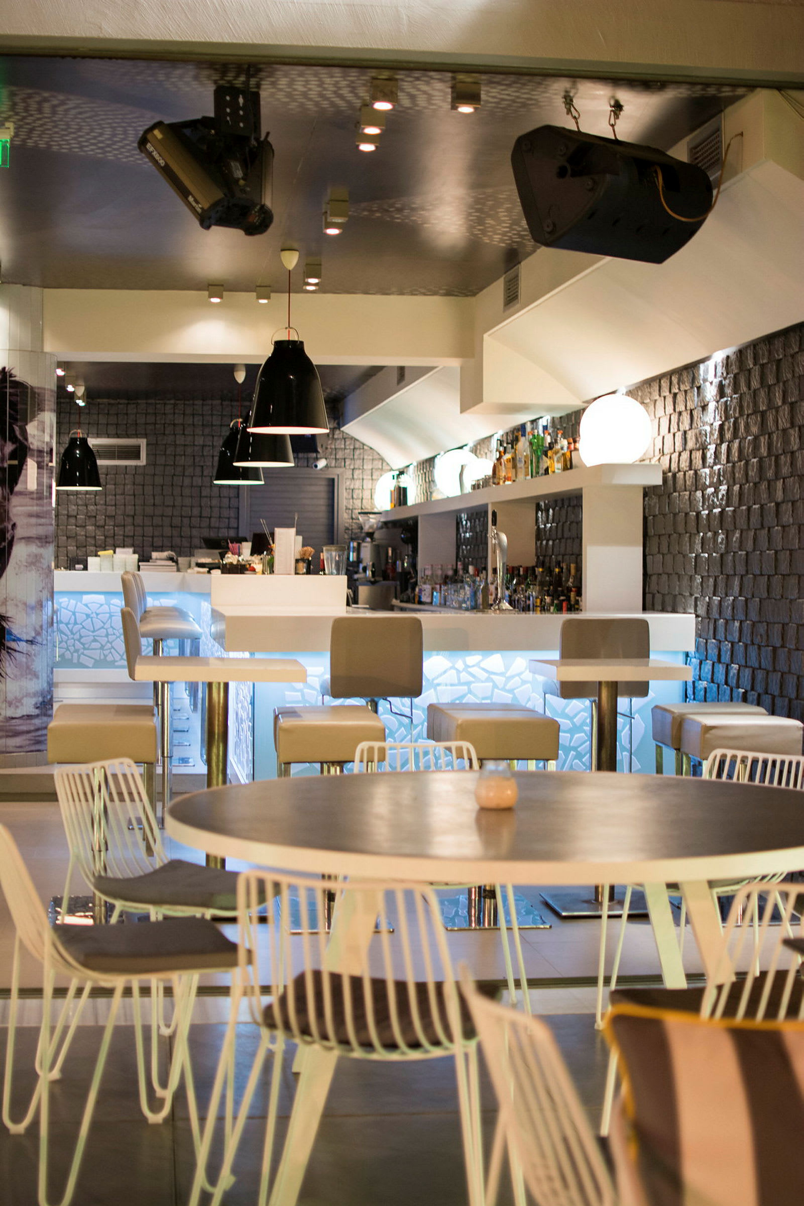 En modern bar med höga stolar, bord och ett belyst serveringsområde. (AI-genererad text)