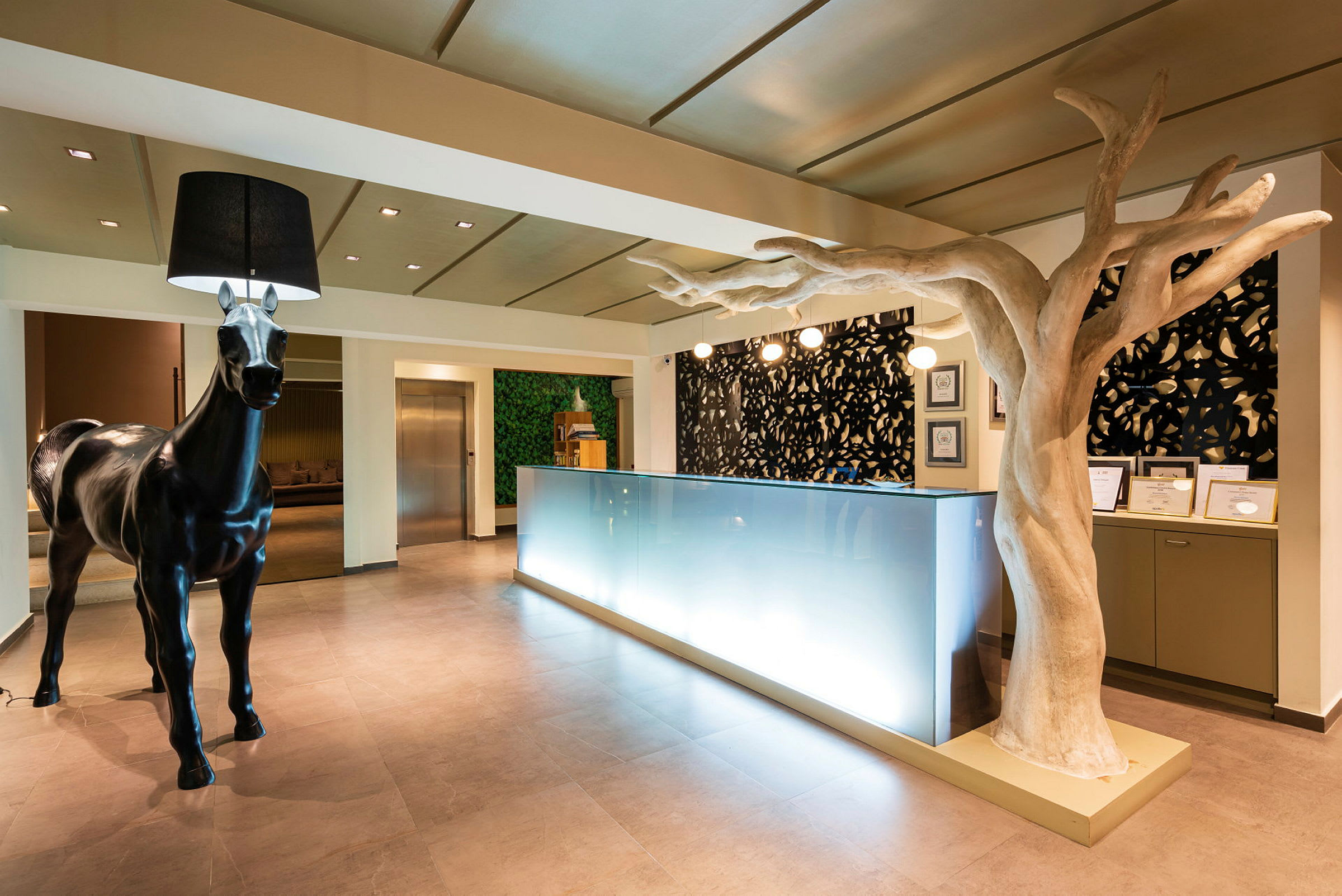 Modern hotellreception med skulptur av en häst och ett träd inomhus. (AI-genererad text)