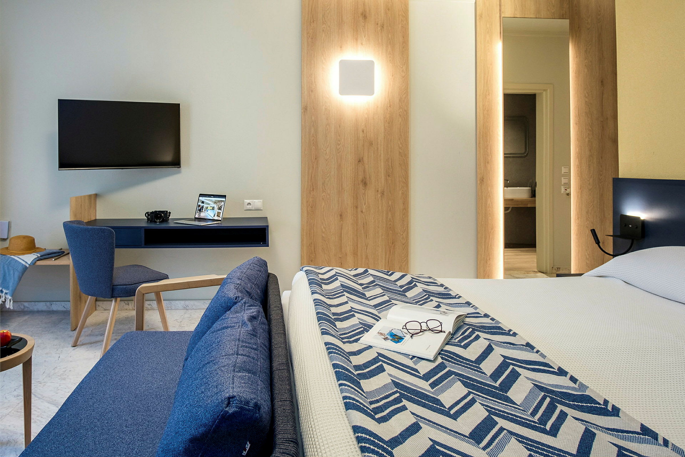 Modernt hotellrum med TV, skrivbord, soffa och säng. (AI-genererad text)
