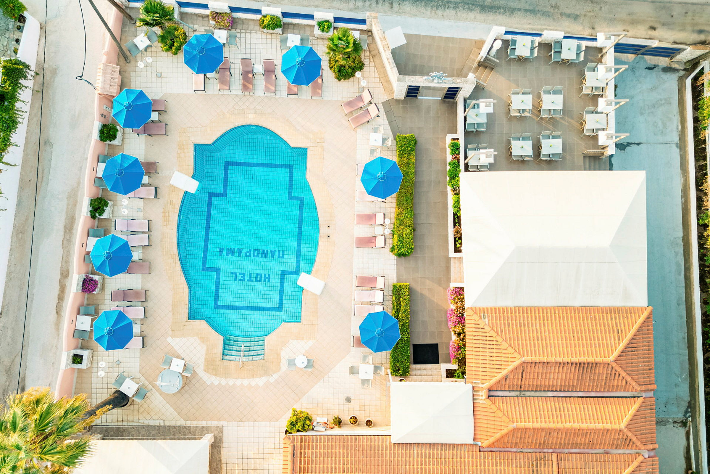 Flygvy av hotellpoolområde med solstolar och parasoller. (AI-genererad text)
