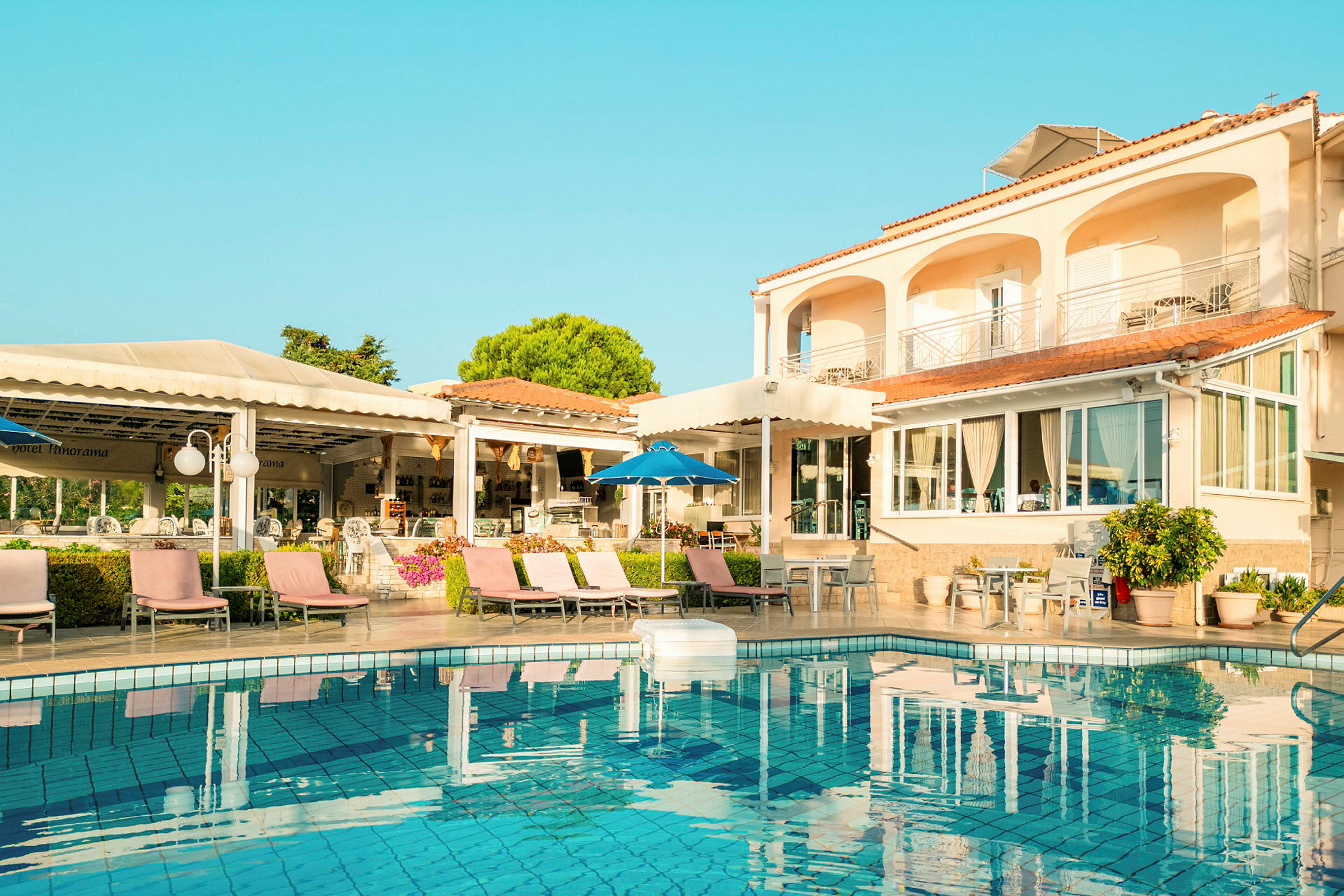 Exteriör av hotell med pool och solstolar. (AI-genererad text)