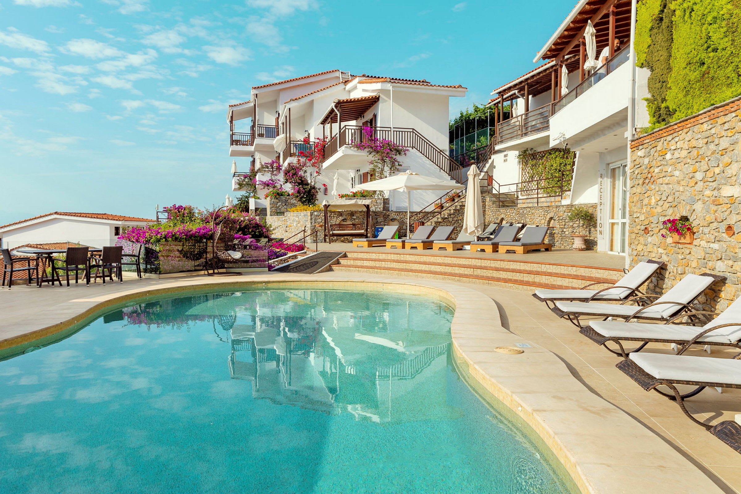 Utomhuspool vid hotell byggt i medelhavsstil med solstolar och blommor. (AI-genererad text)