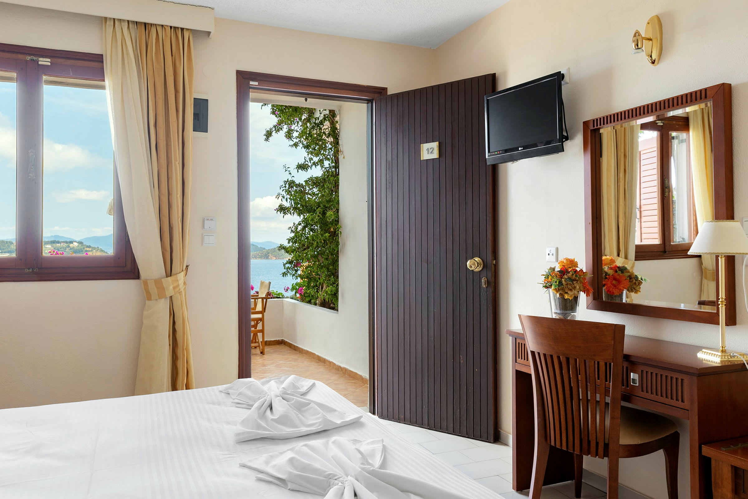 Hotellrum med dörr till balkong, havsutsikt. (AI-genererad text)