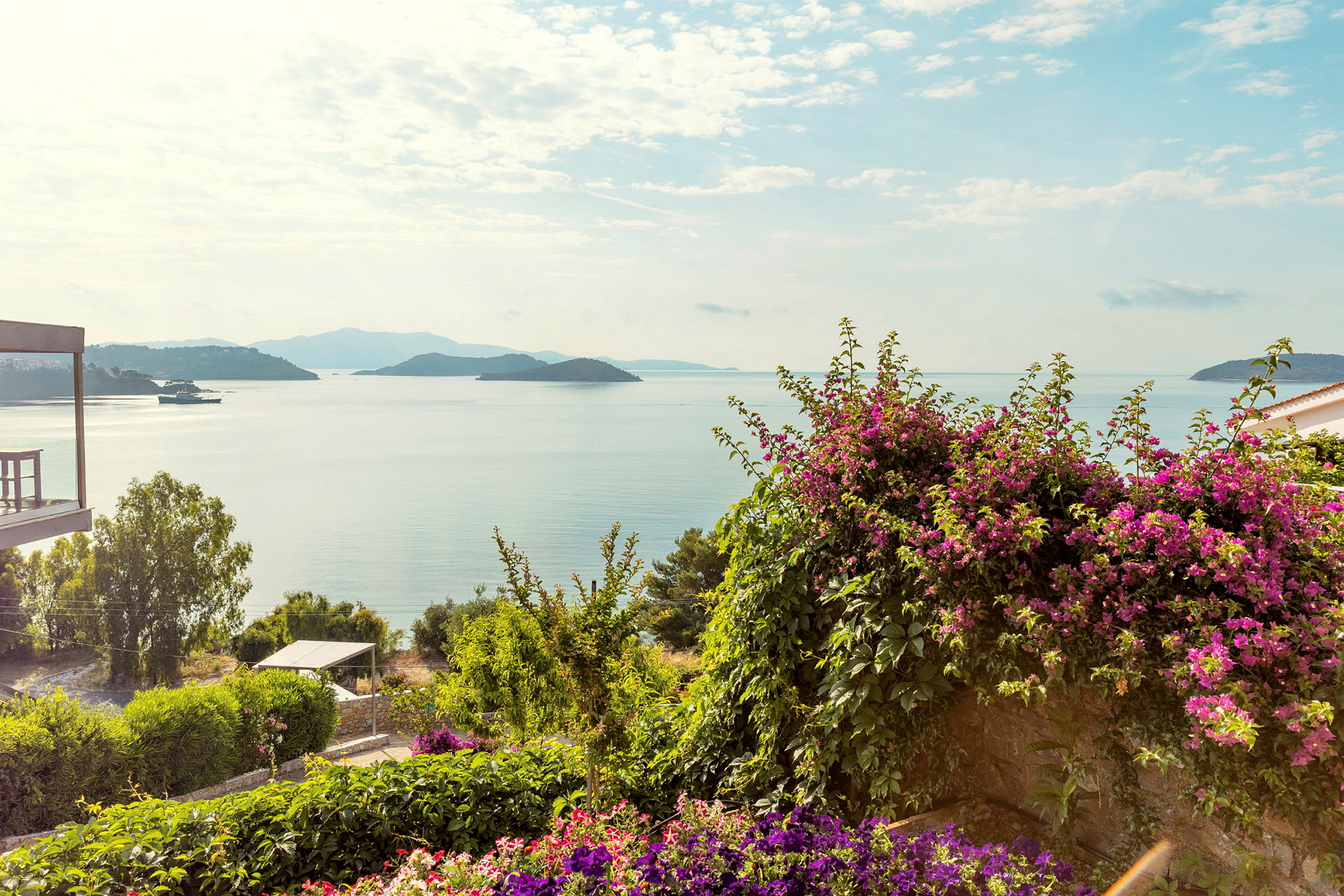 Utsikt över havet med öar i fjärran, omgiven av grönska och blommor. (AI-genererad text)