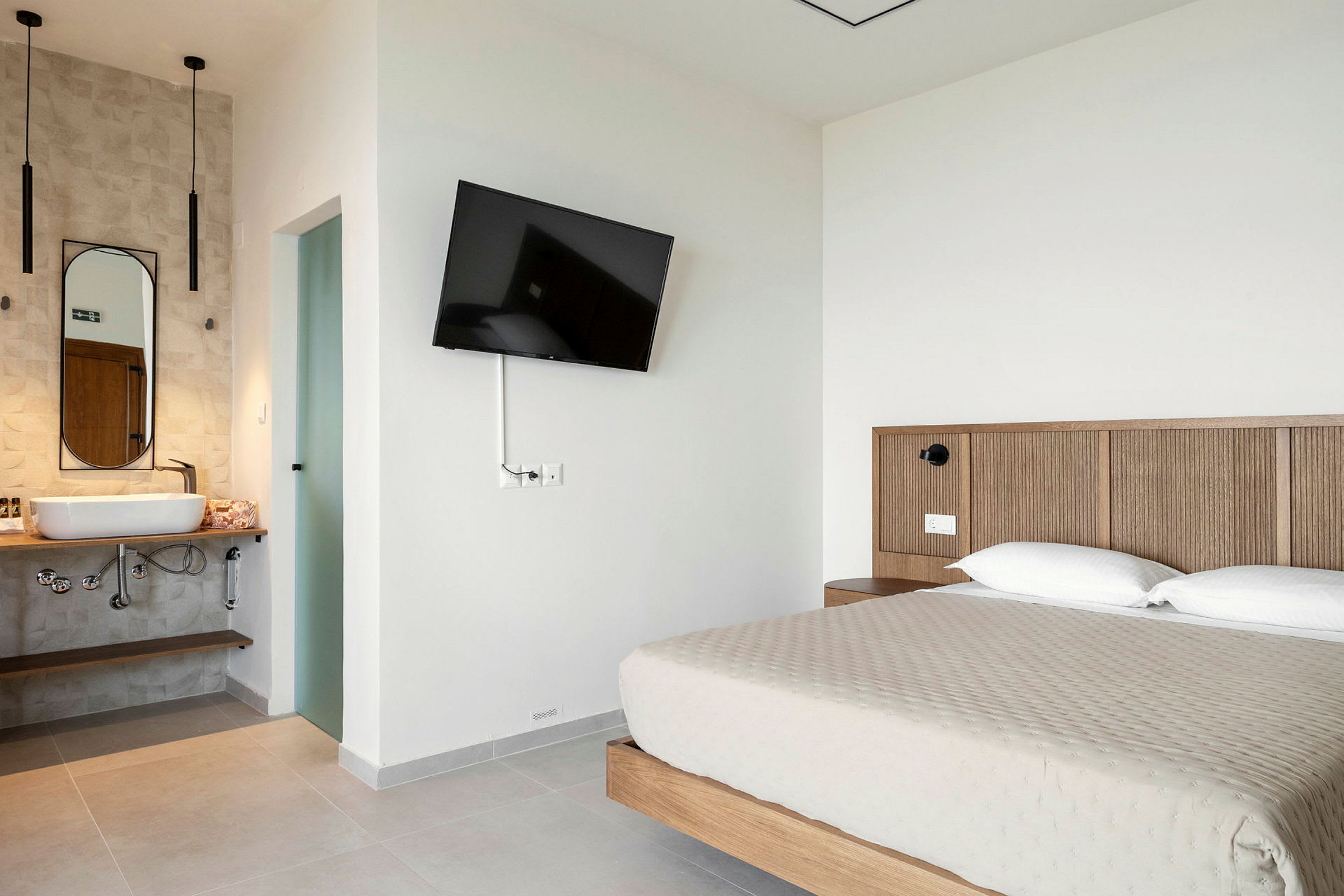 Hotellrum med en dubbelsäng, väggmonterad TV och ett öppet badrum. (AI-genererad text)